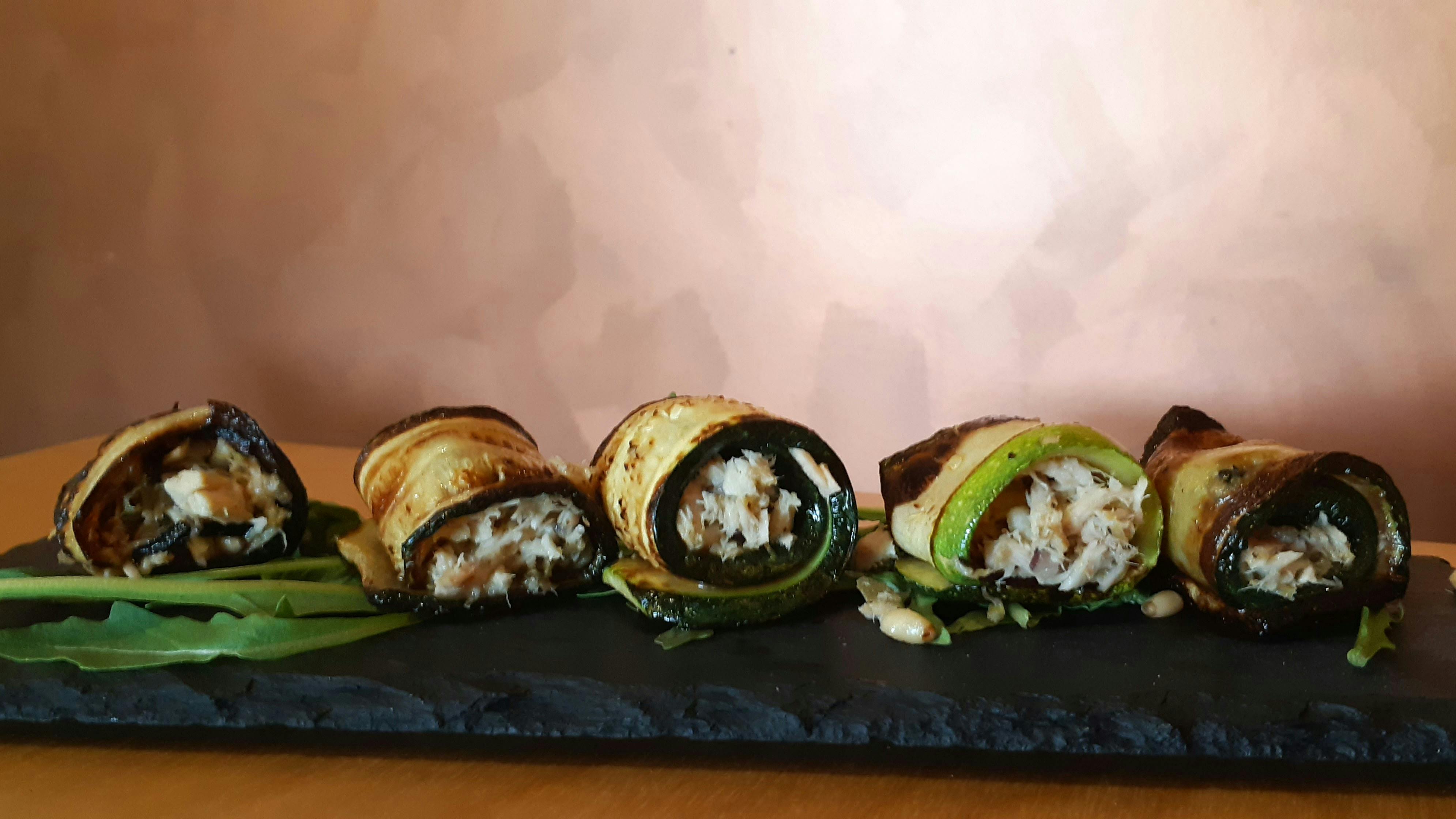 Zucchini slices wrapped around tuna, pine nuts and lemon on black slate