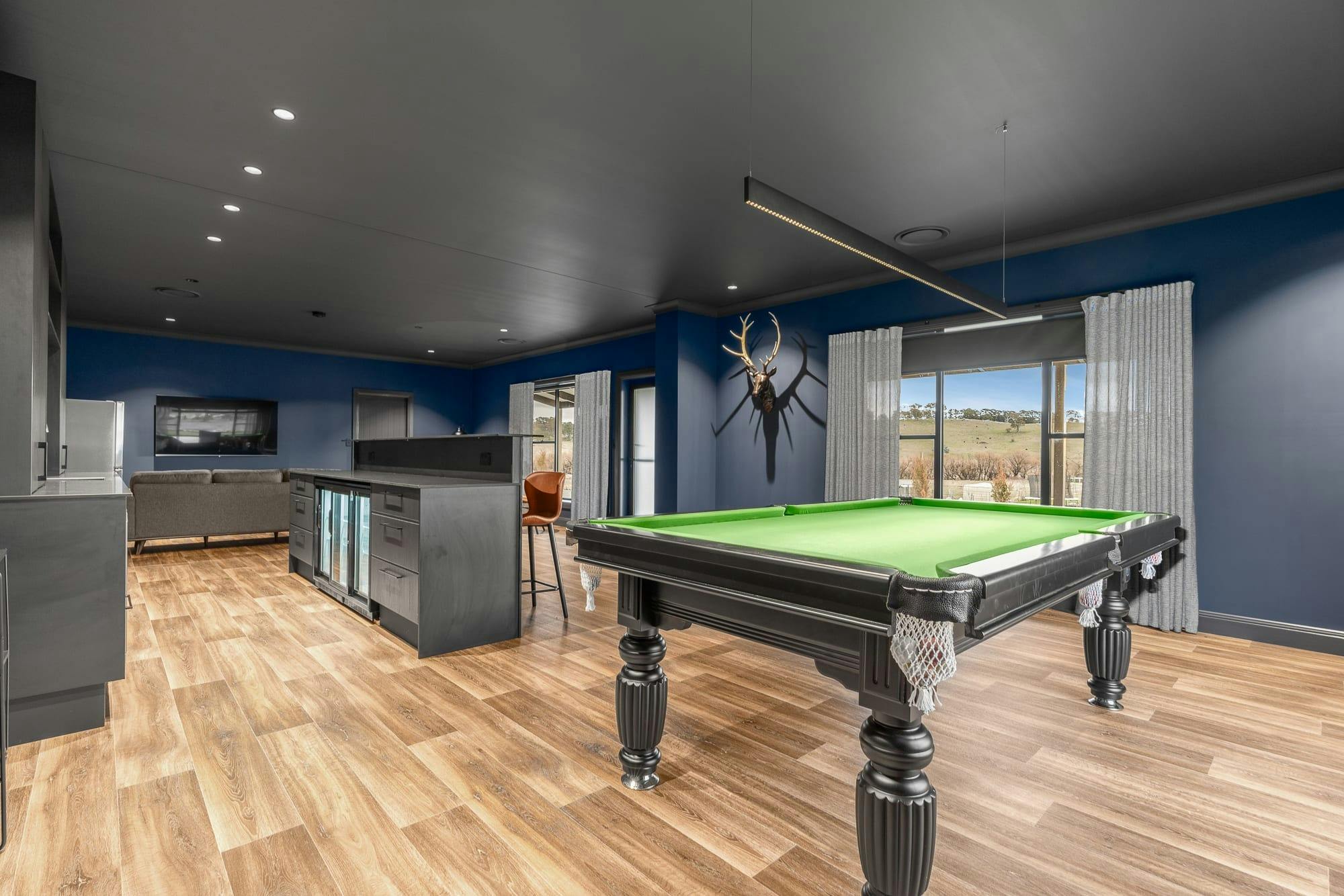 Dark walls & ceiling, wooden floors and pool table surrounded by unreal views