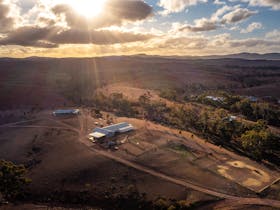 Aerial view of farmstay and Flinders Ranges at sunset, with Shearers Quarters accommodation and shed