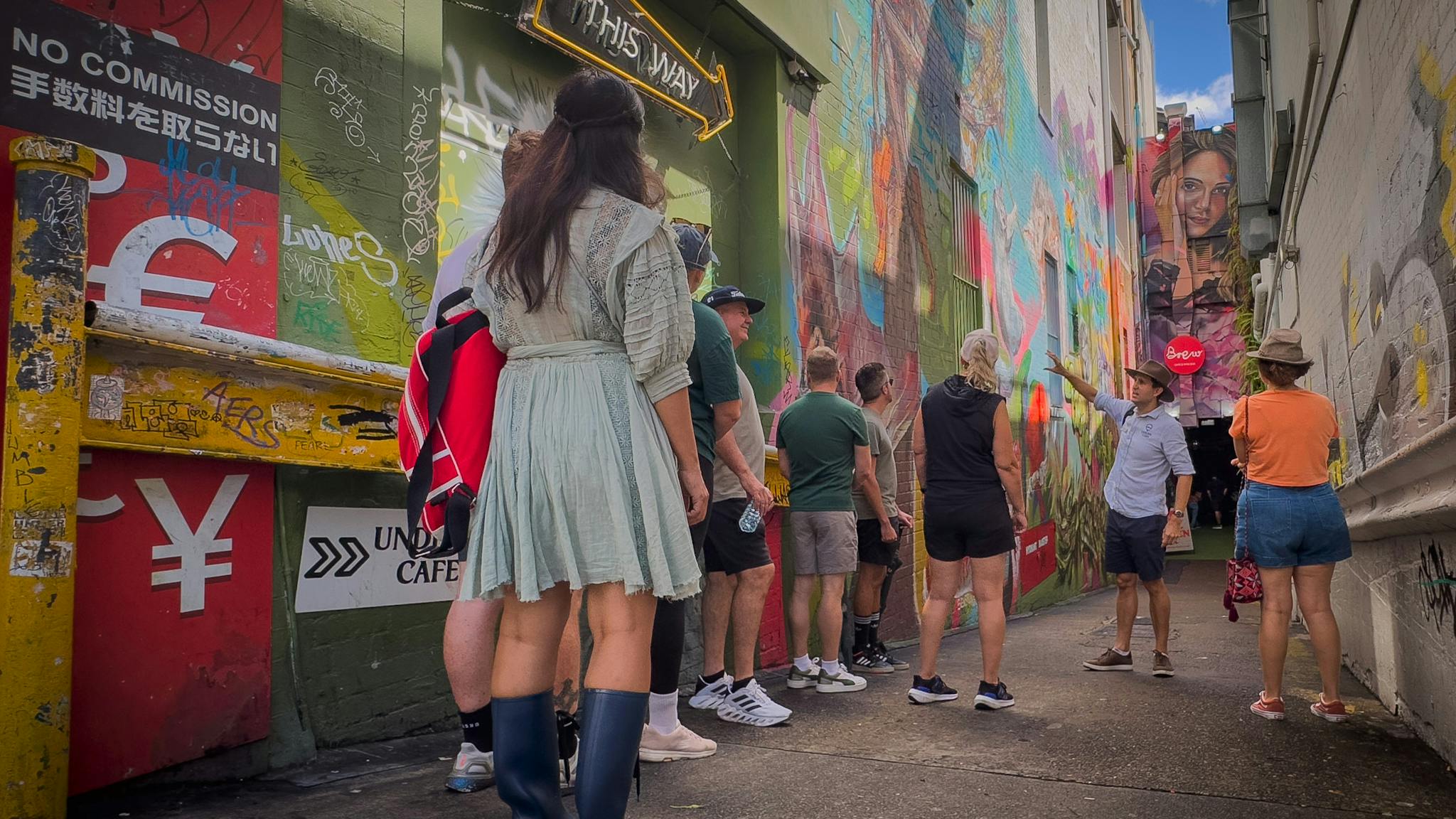 Street art covering walls of laneway. Group of people listening to Brisbane Tour Guide. Street art covering walls of laneway. Group of people listening to Brisbane Tour Guide.