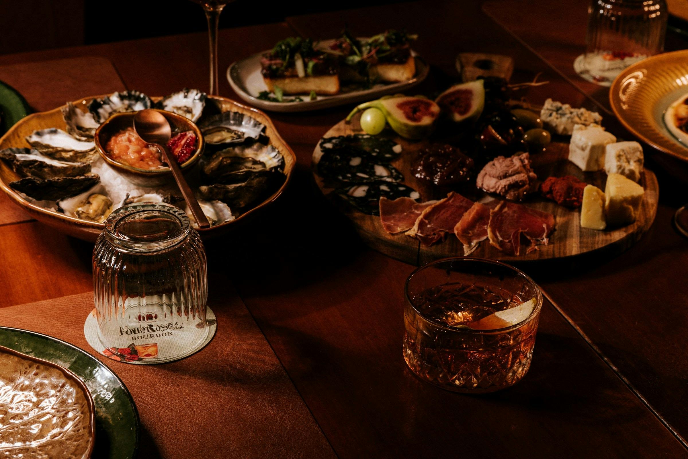 Dining table with fresh oysters, sliced steak and wine glasses