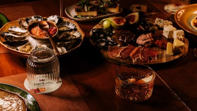 Dining table with fresh oysters, sliced steak and wine glasses
