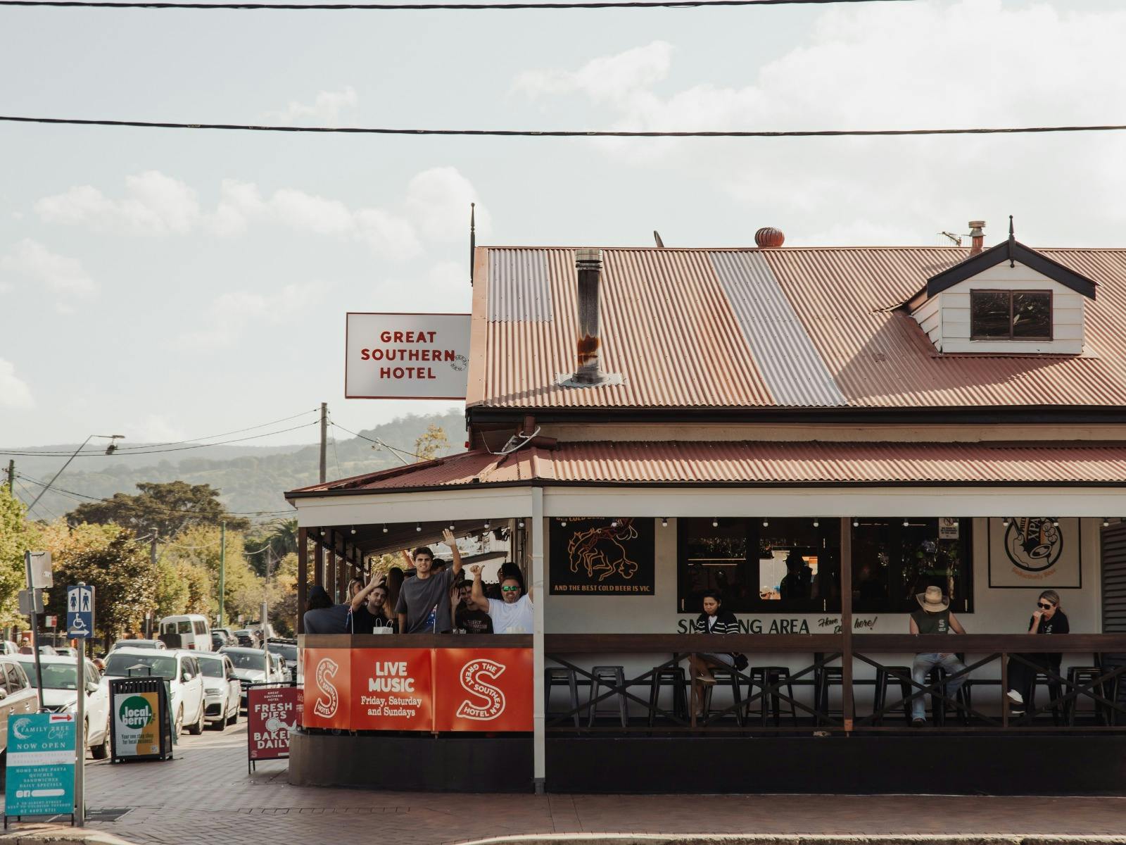 Great Southern Hotel Berry building with red and white signage and patrons standing on the balcony o