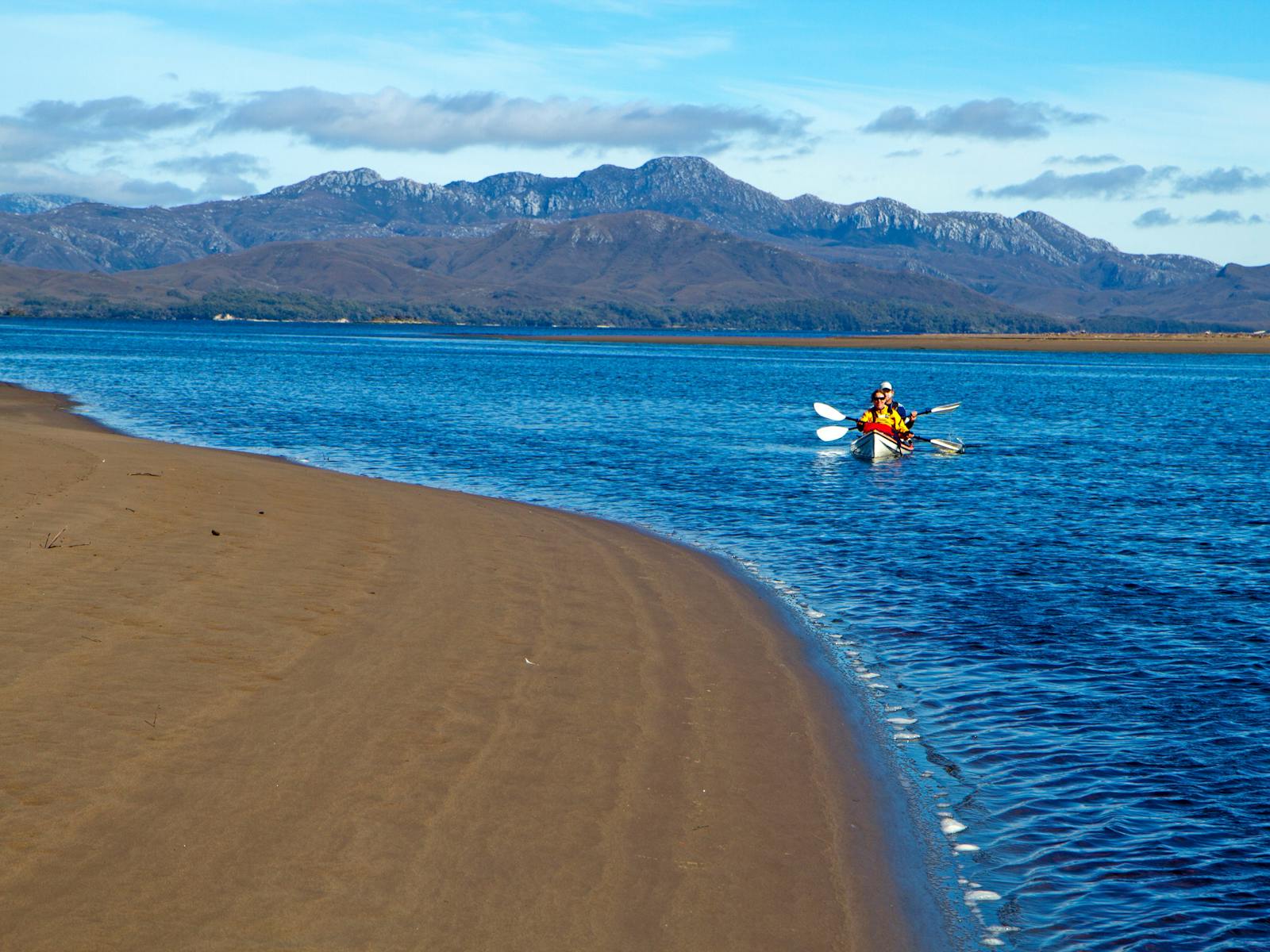 Kayakers paddling near a sand spit on Port Davey