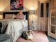 Woman reading while sitting on the bed with a dog seated by the bed, table lamps lit