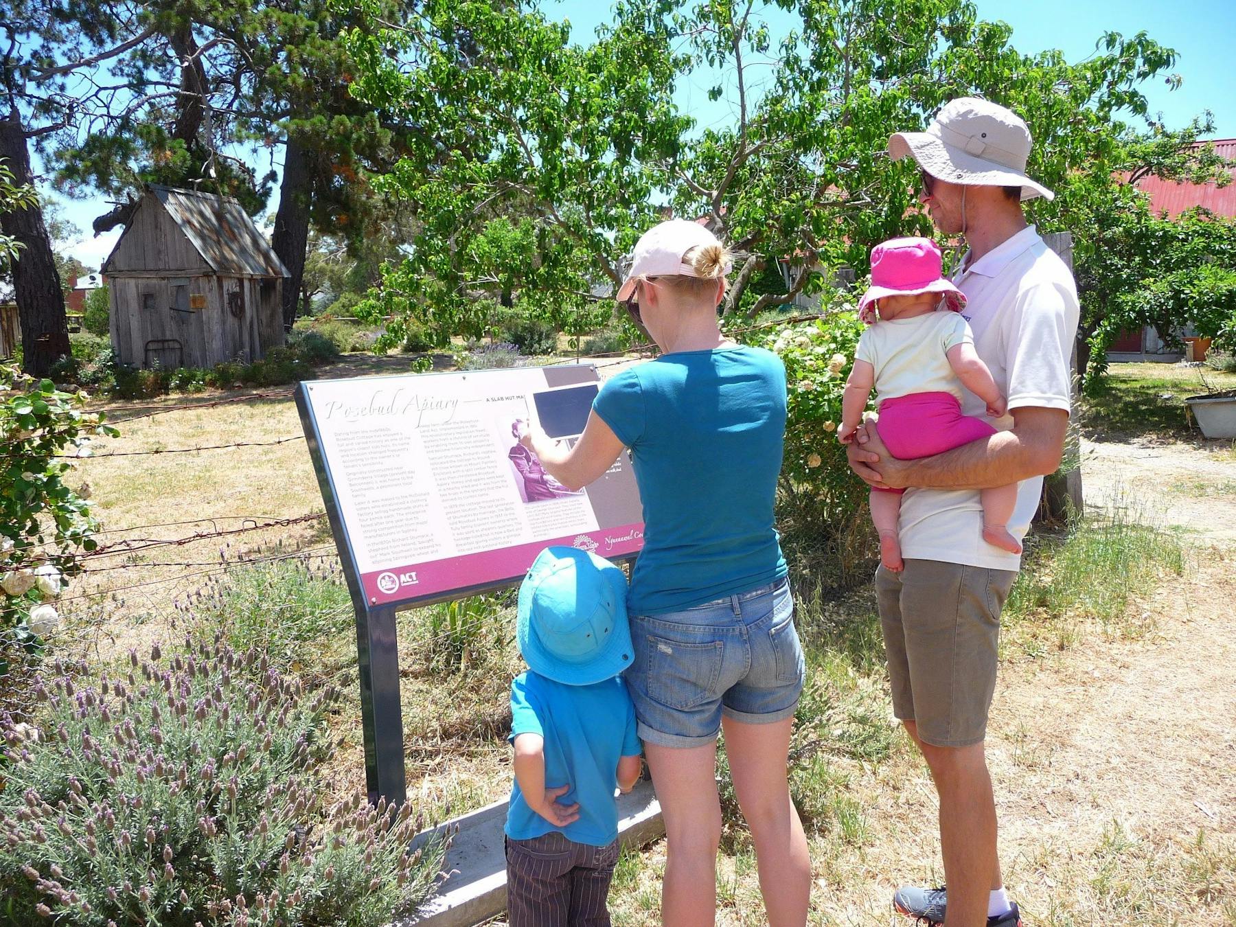 Woman holding device infront of sign with man and two children