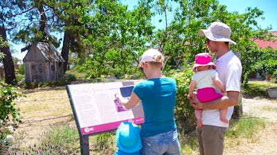 Woman holding device infront of sign with man and two children