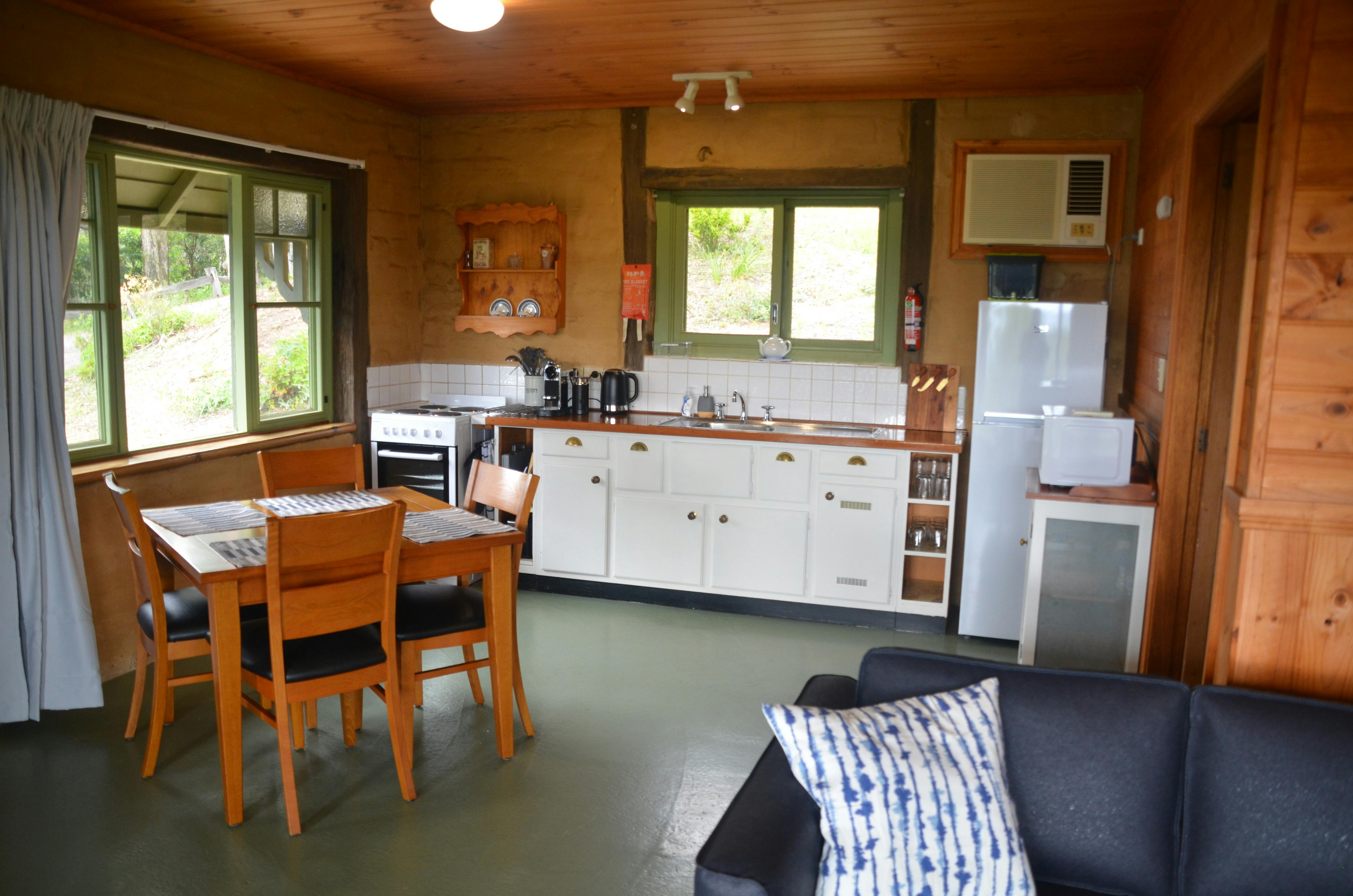 A kitchen and meals area within a rustic mud-brick cottage