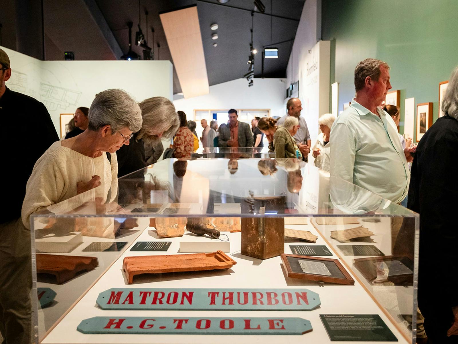 People viewing objects and photographs in the exhibition 'Bloomfield 1925-2025'