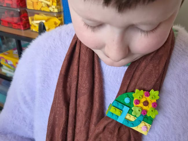 a child looking at a badge built from lego blocks
