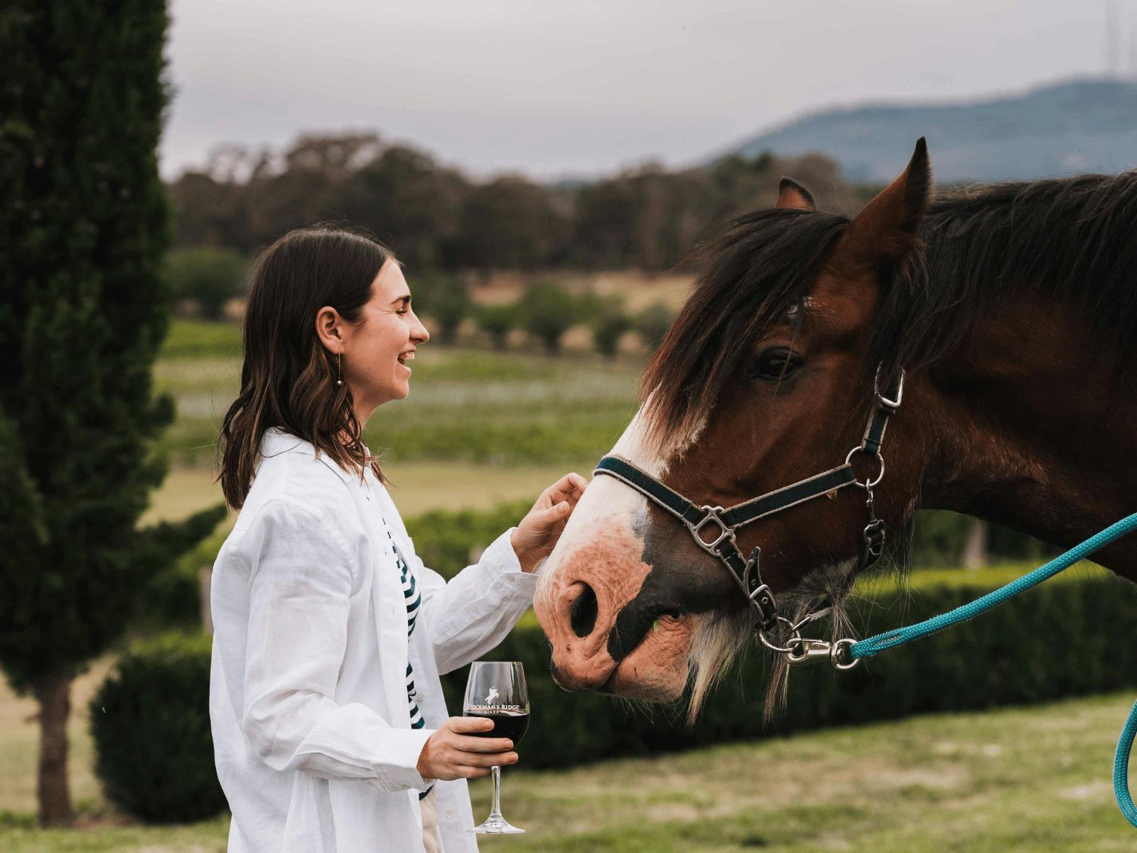 Girl drinking wine and petting a horse at Stockman's Ridge Wines