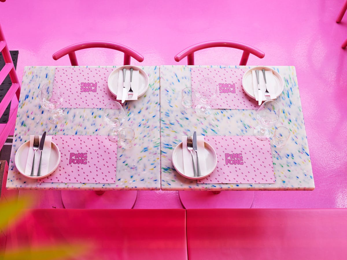 A birds eye view of a set dining table for four people inside PingPong's pink room