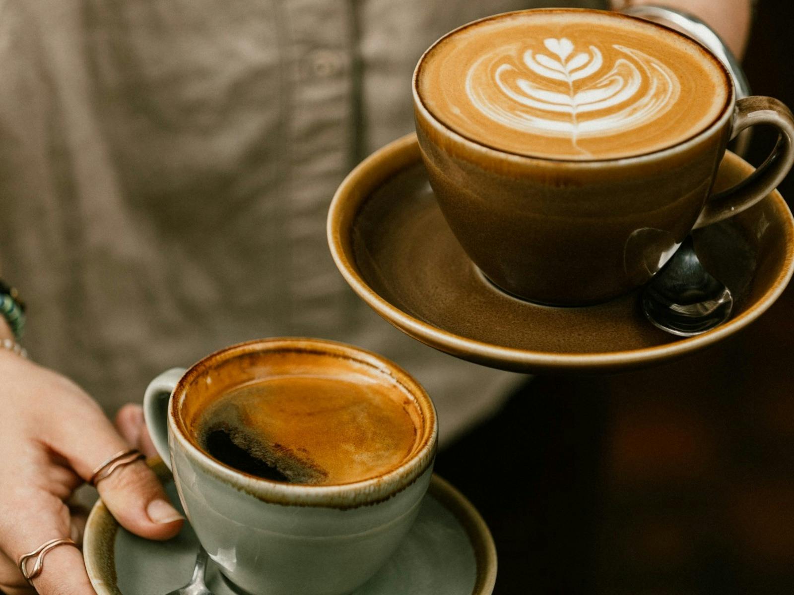 two coffees being carried to tables