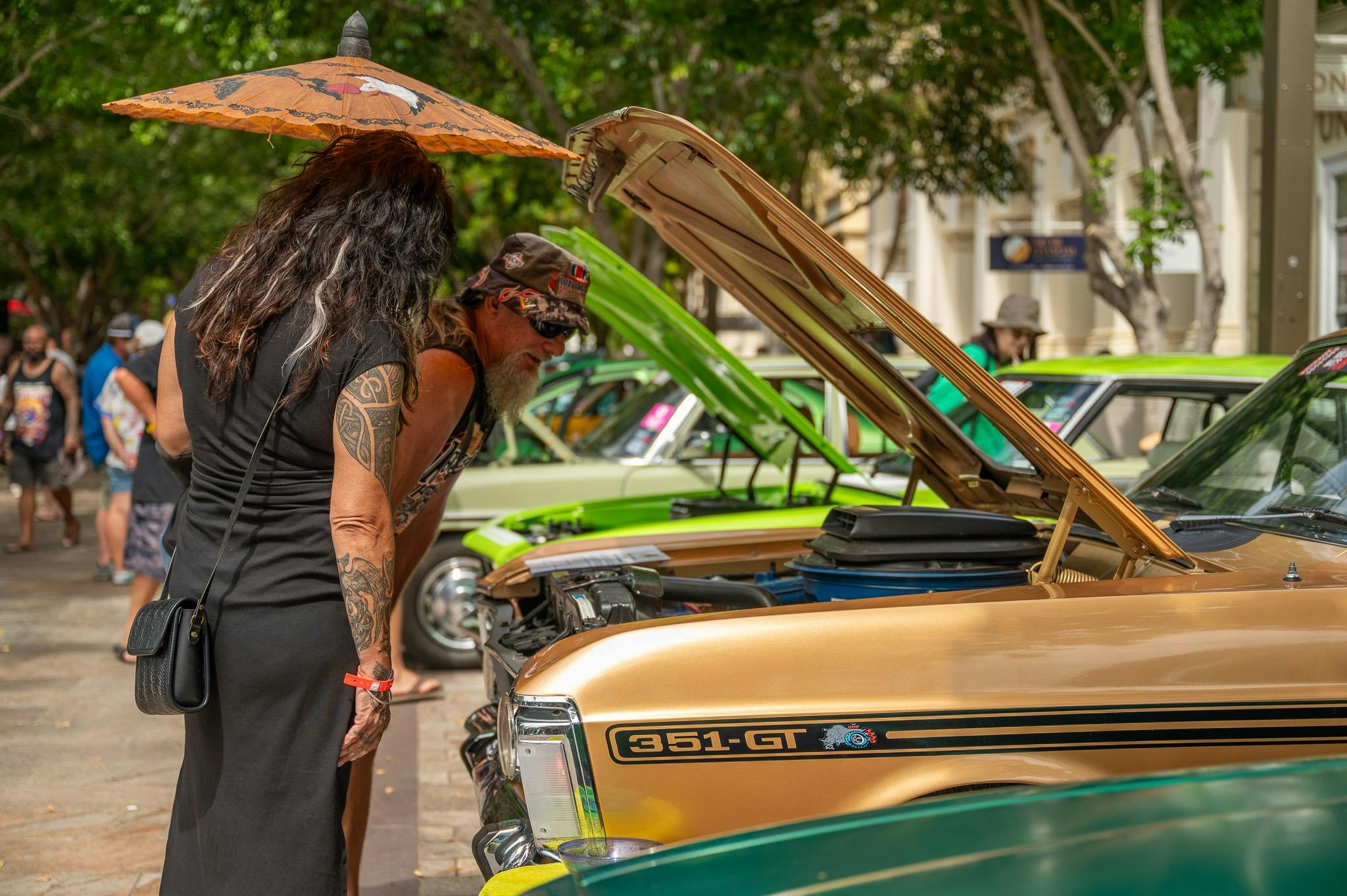 People viewing classic cars with open bonnets during Rockynats.
