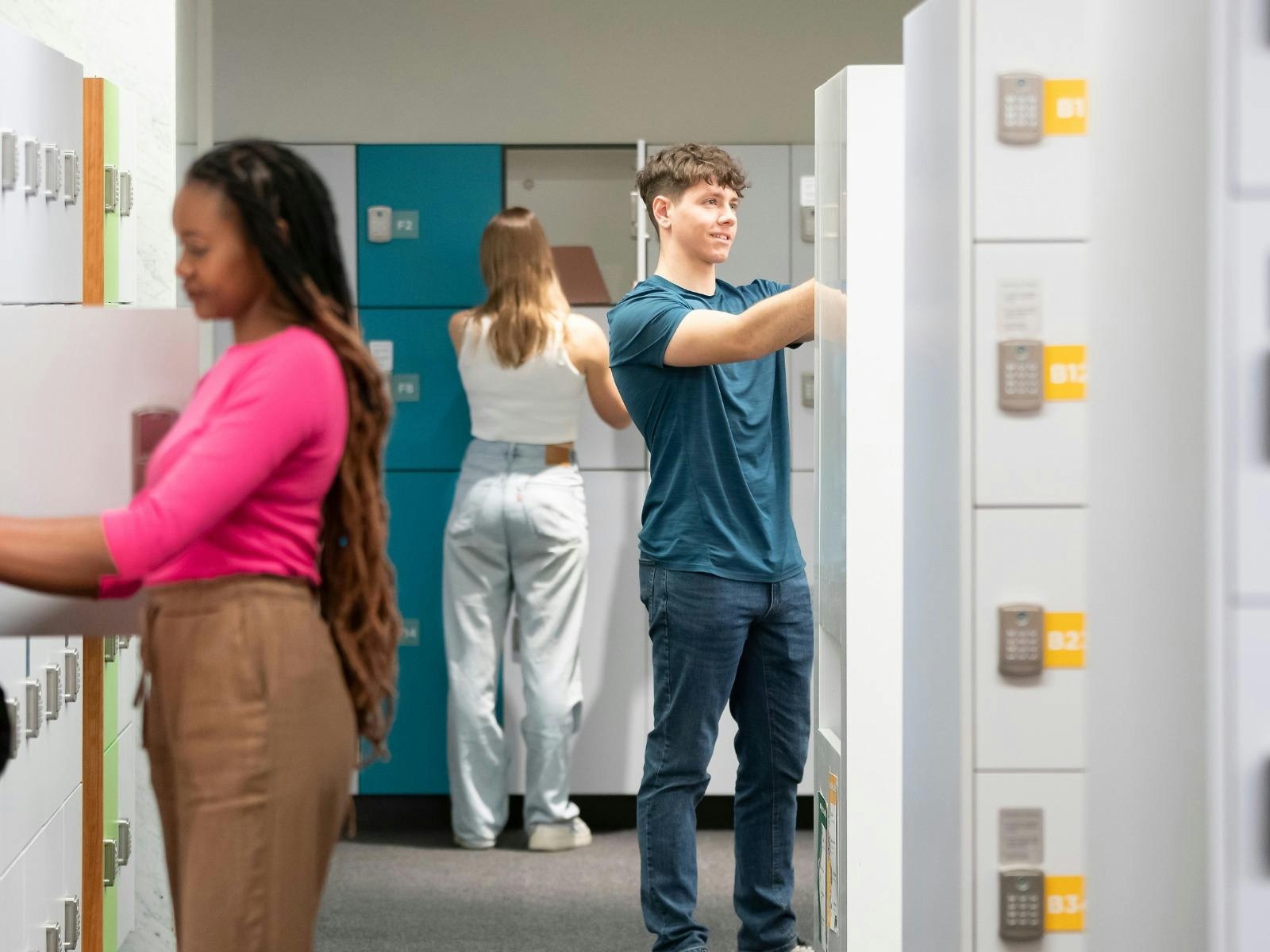 Three students in the locker bay area, storing their personal belongings at the Library.
