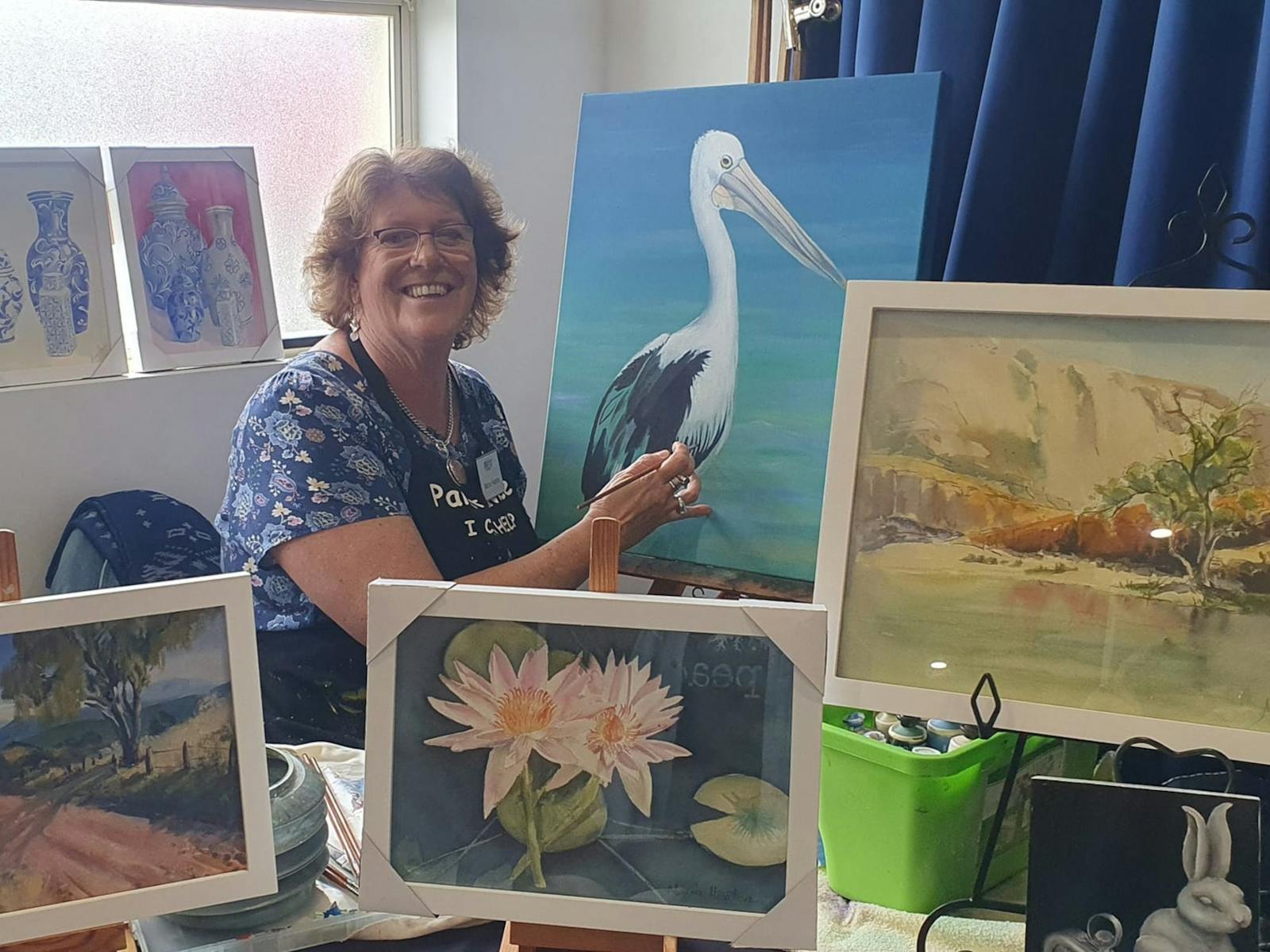 Maria sitting her studio surrounded by her paintings