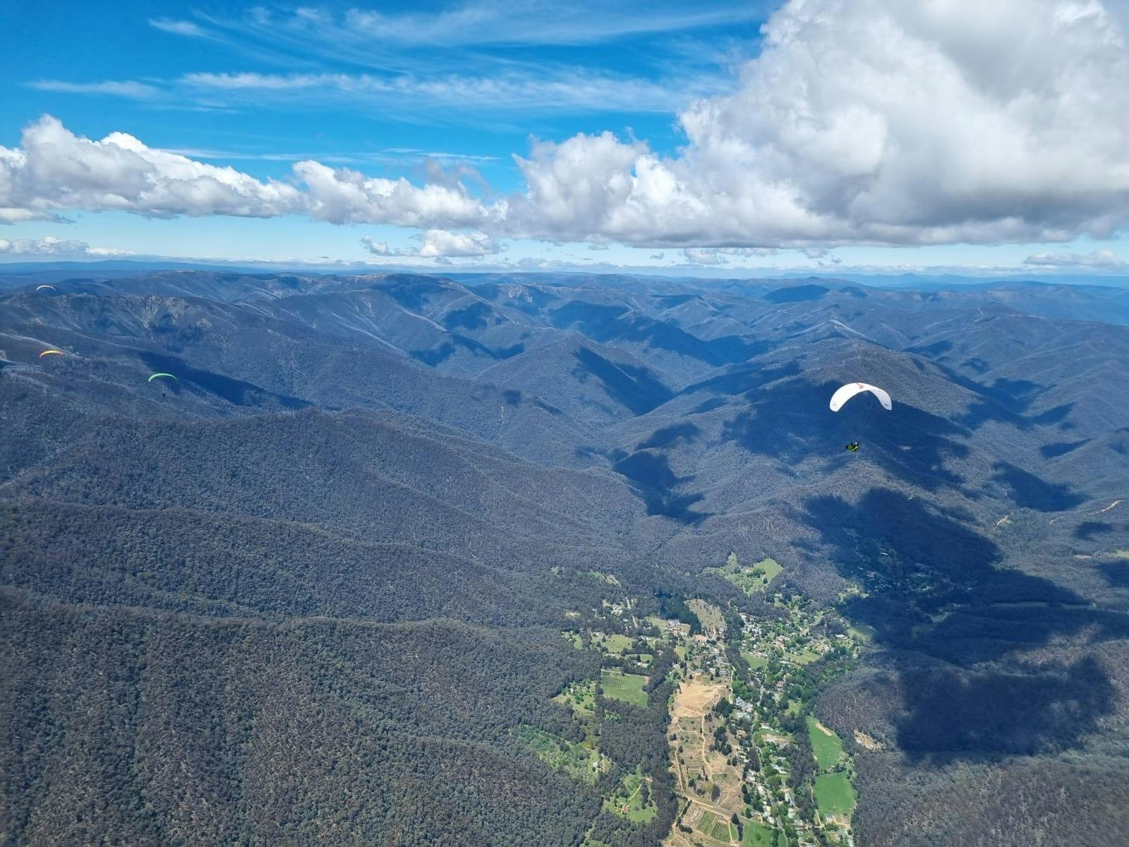 A paraglider is flying above mountains and valleys of North East Victoria