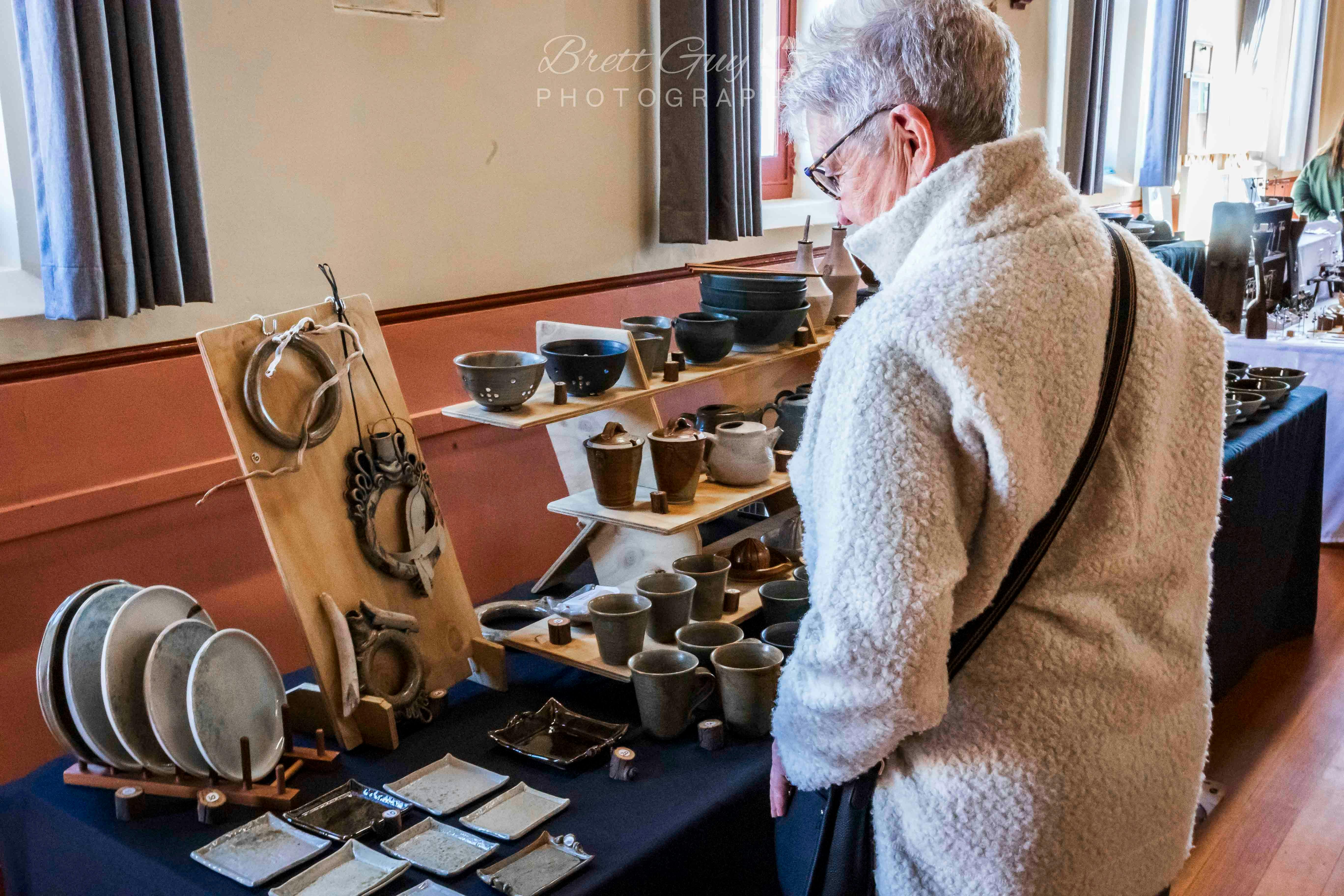 A woman looks at pottery items on a stall