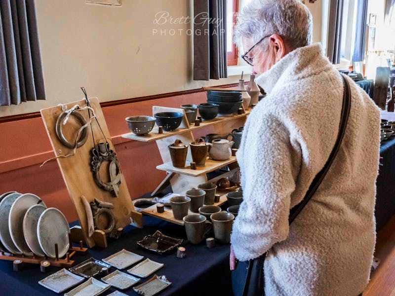 A woman looks at pottery items on a stall