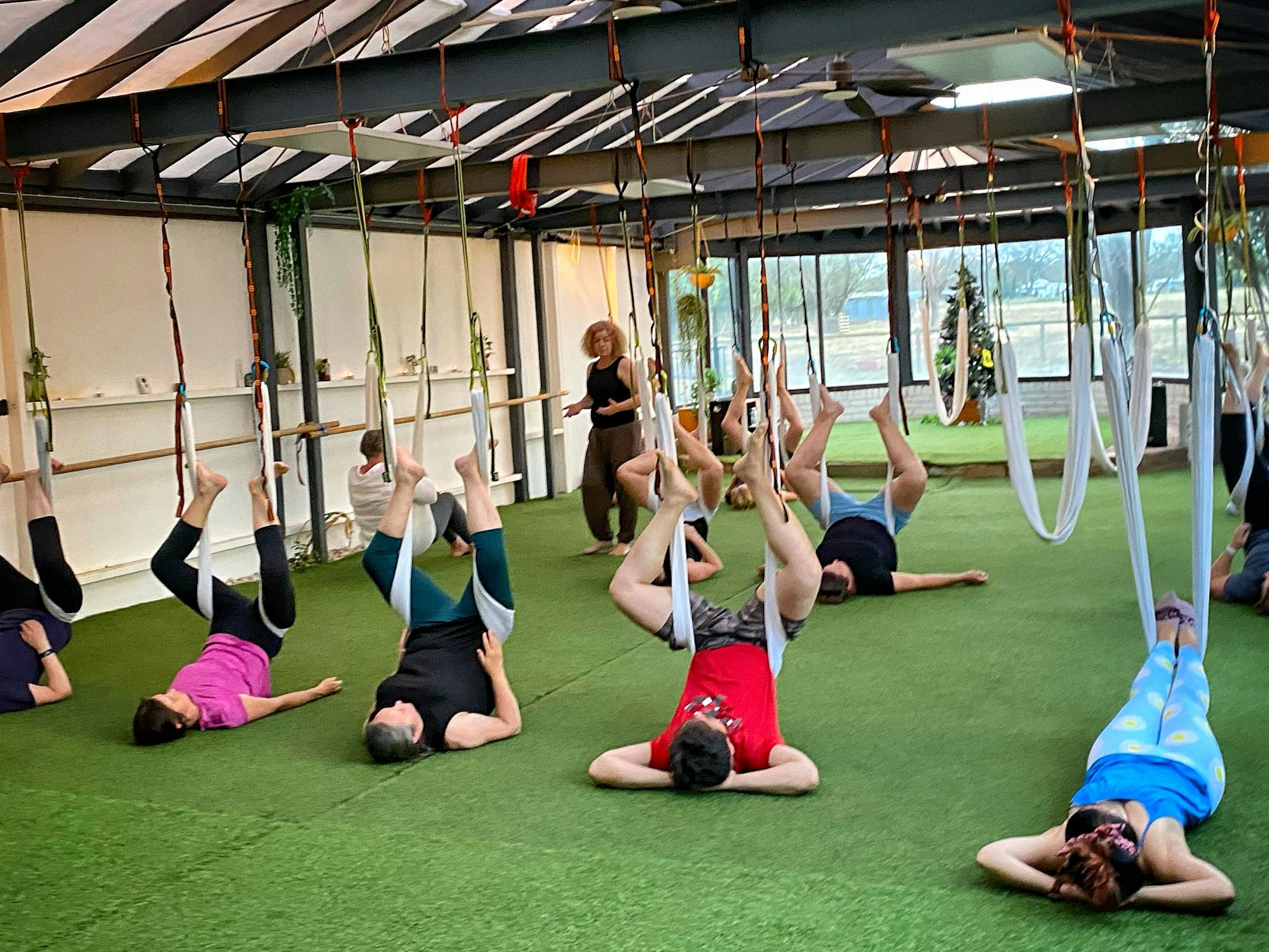 People hanging from aerial yoga silks low to the ground