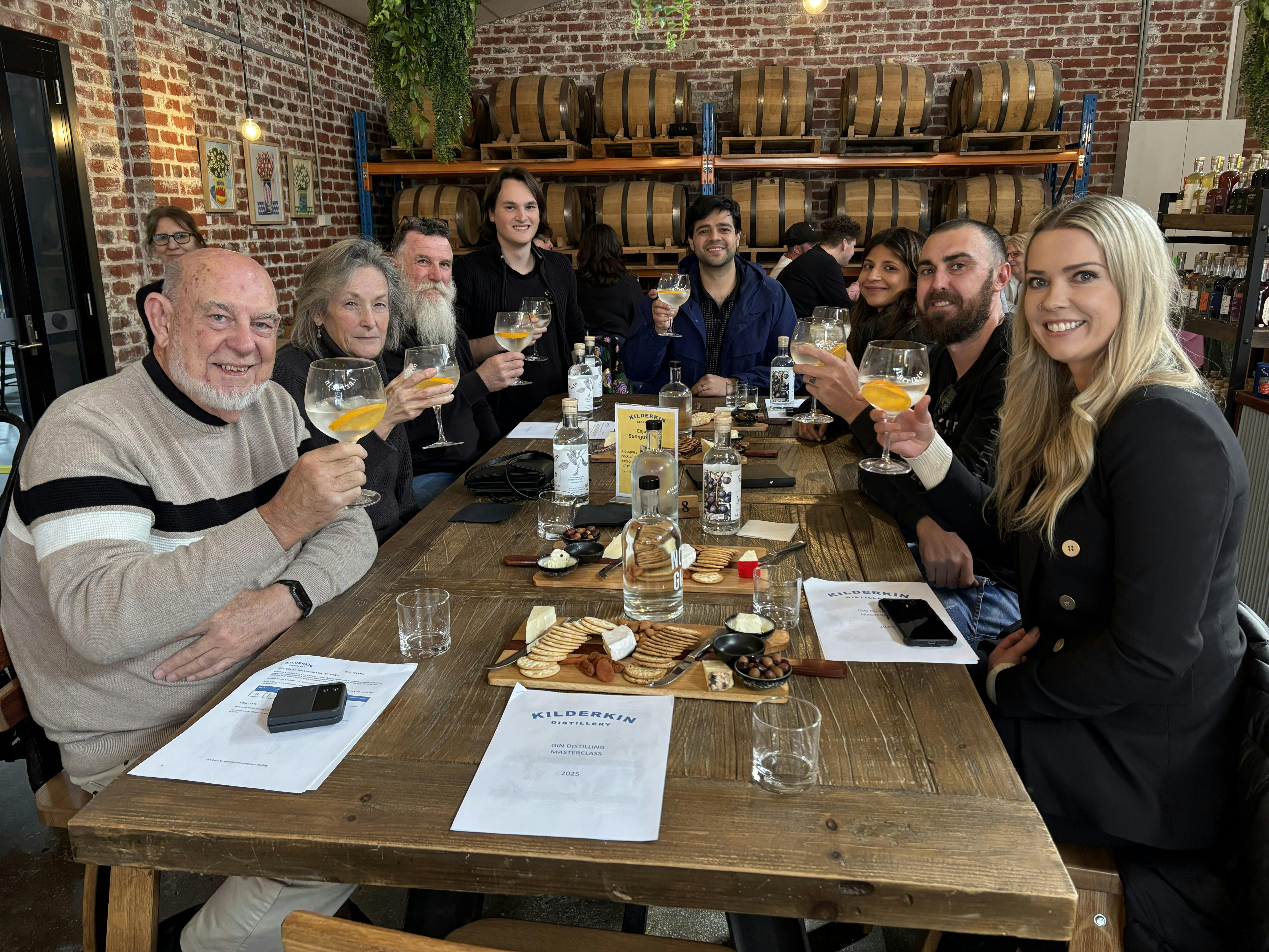 Group of eight people sitting having gin and tonics with cheese