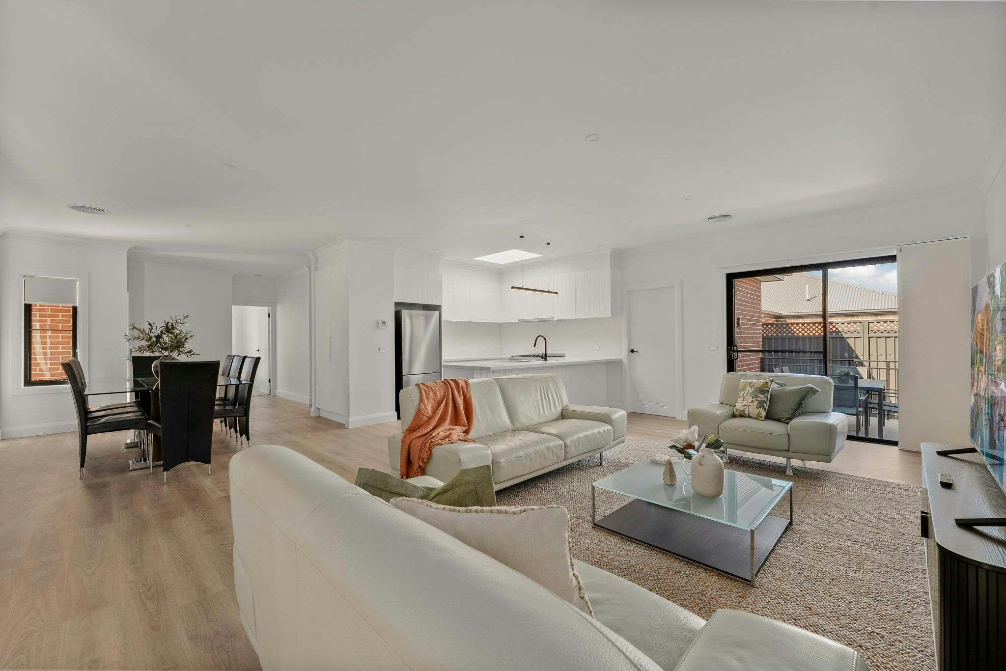 Living area with 3 couches, large dining table and chairs, kitchen