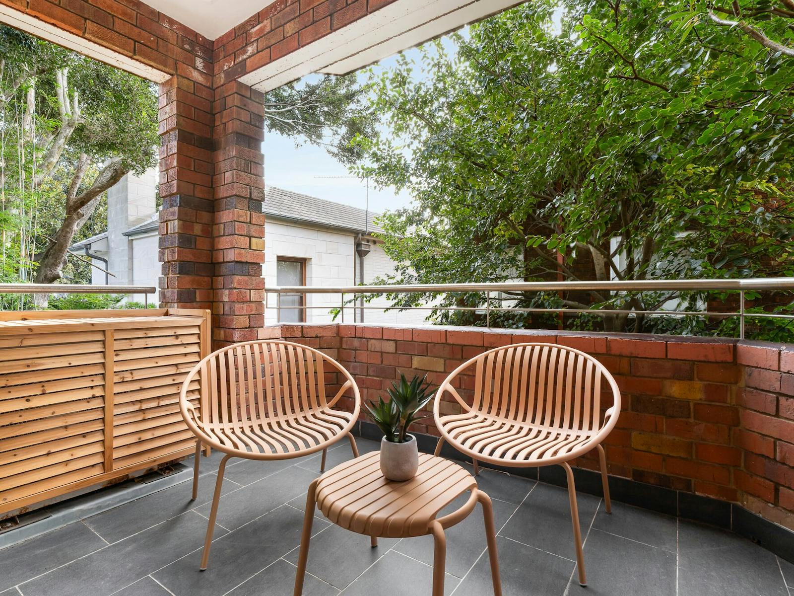 Spacious covered, paved balcony with rattan outdoor furniture set - 2 chairs and a small table.