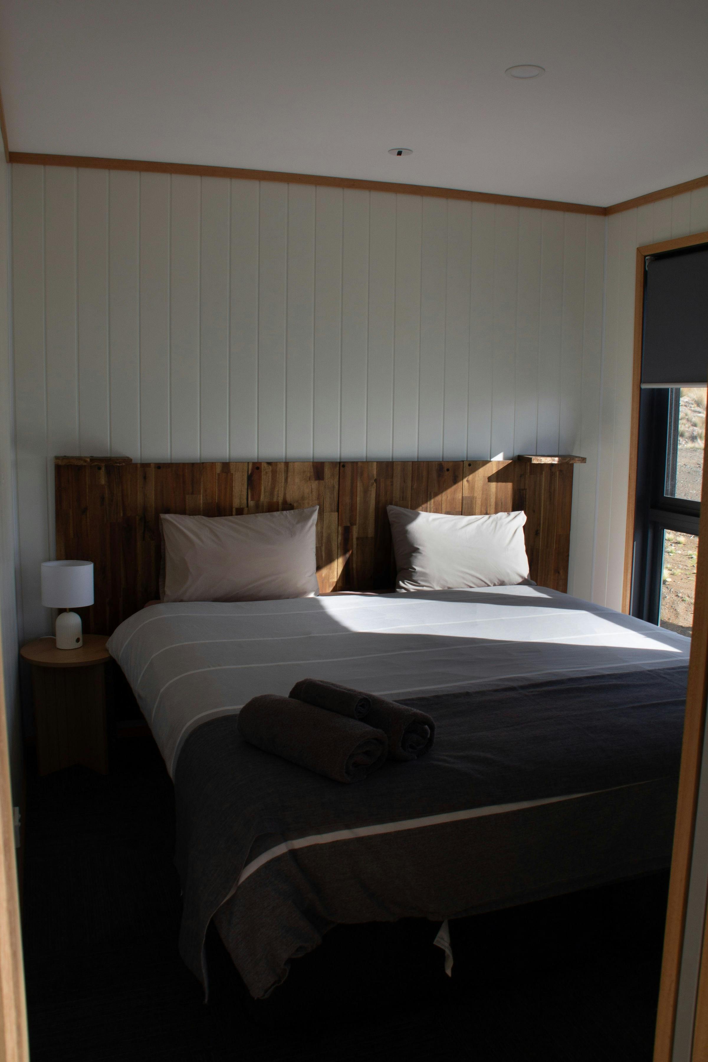 Bedroom with queen bed, timber walls and bedside tables