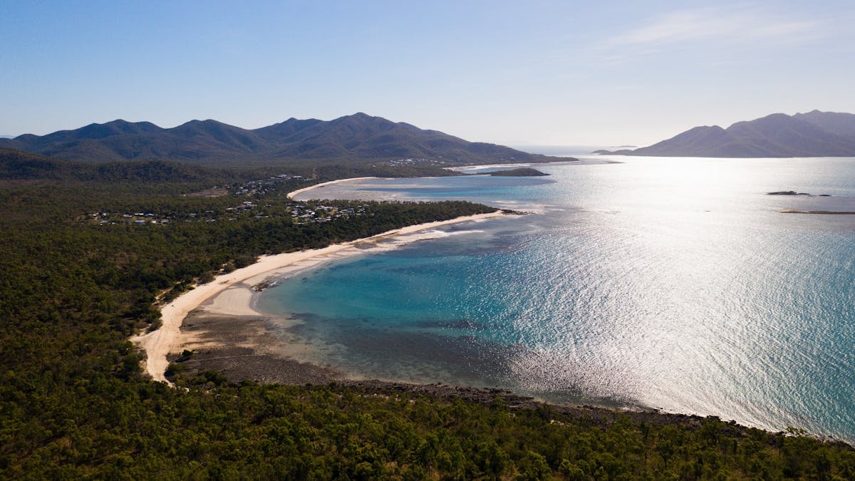 Aerial view of the calm waters of Dingo Beach and surrounding green landscape