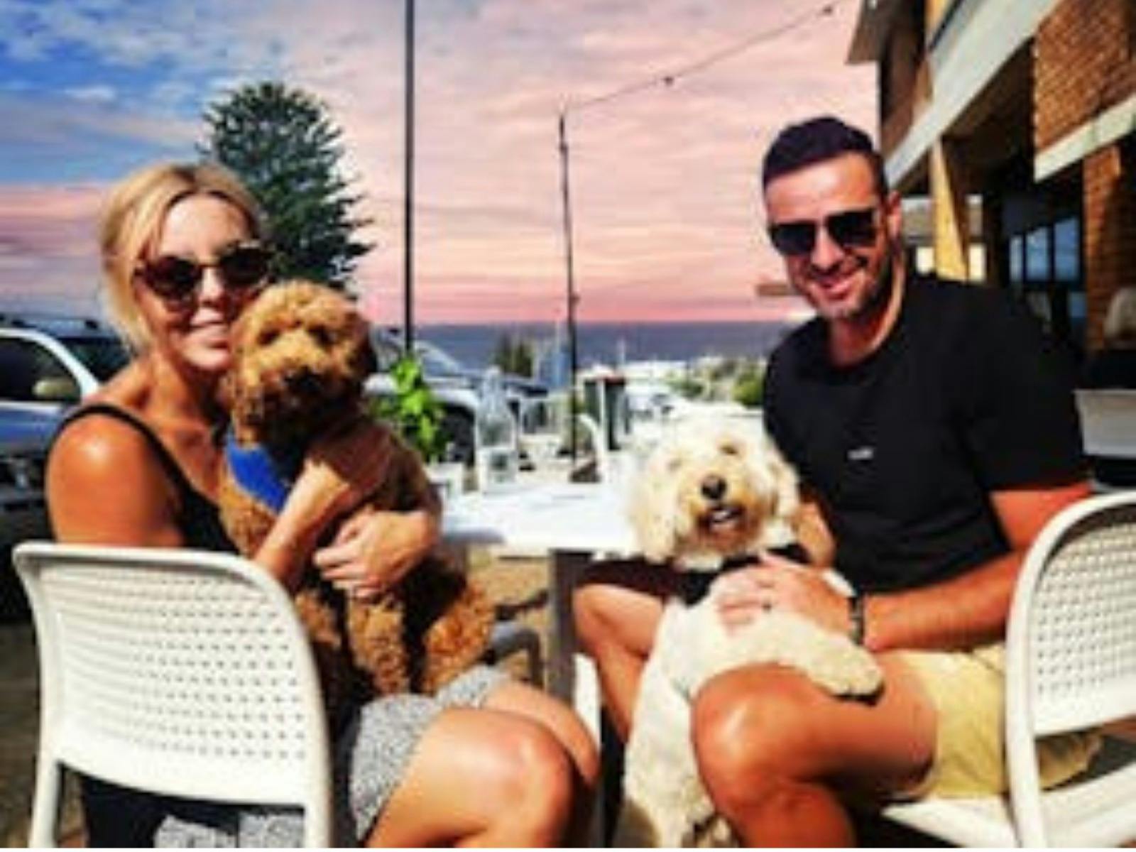 A man and a woman sitting at a table holding their dogs.