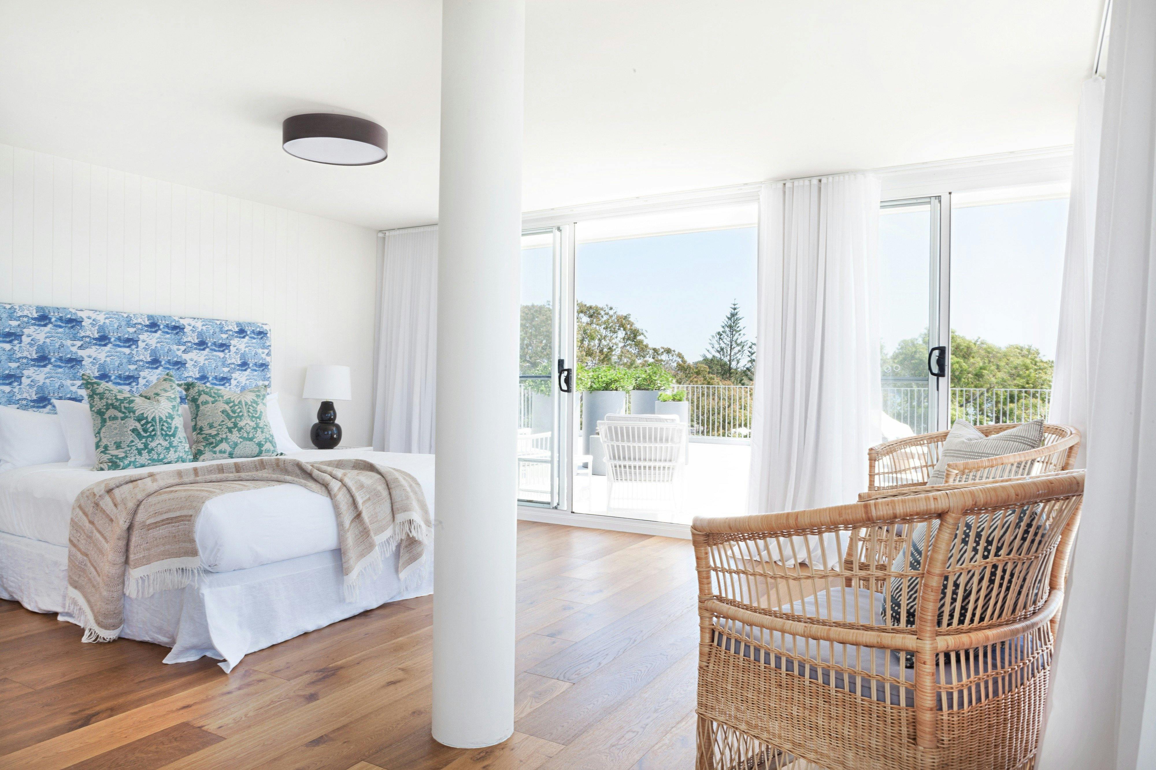 Bed to the left, timber flooring, a bright and airy room with patio access.