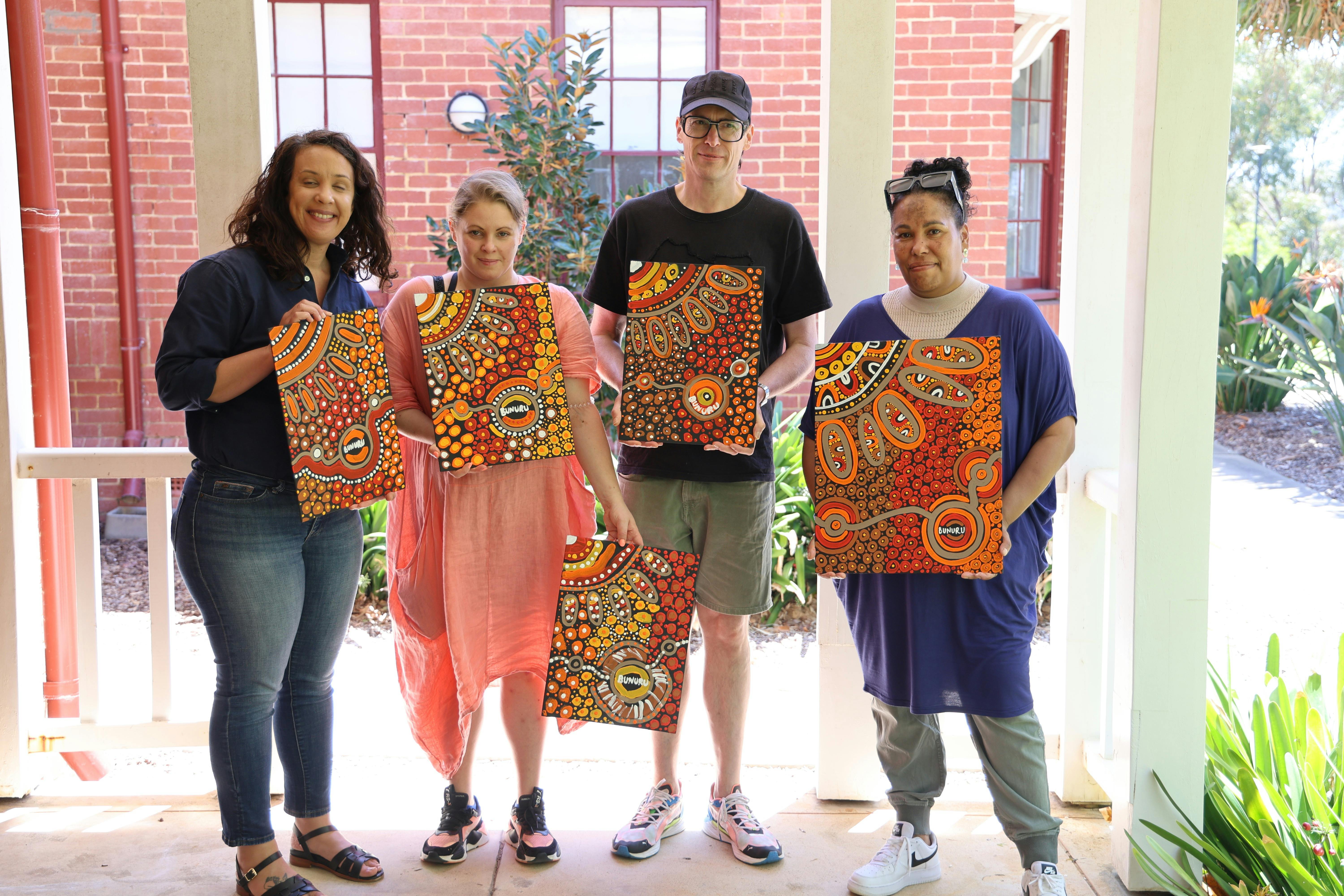 Workshop participants holding their aboriginal artwork