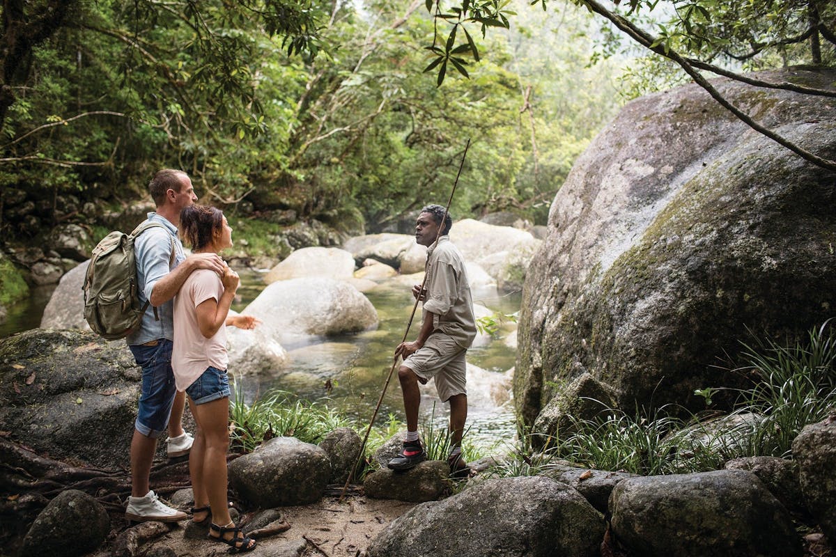 Aboriginal guide at Mossman Gorge, standing by the water with guests.