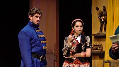 a young man in blue army coat and young girl in traditional Spanish dress look shocked