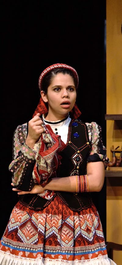 a young man in blue army coat and young girl in traditional Spanish dress look shocked