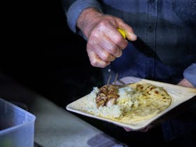 Person squeezing lemon on a Greek inspired meal
