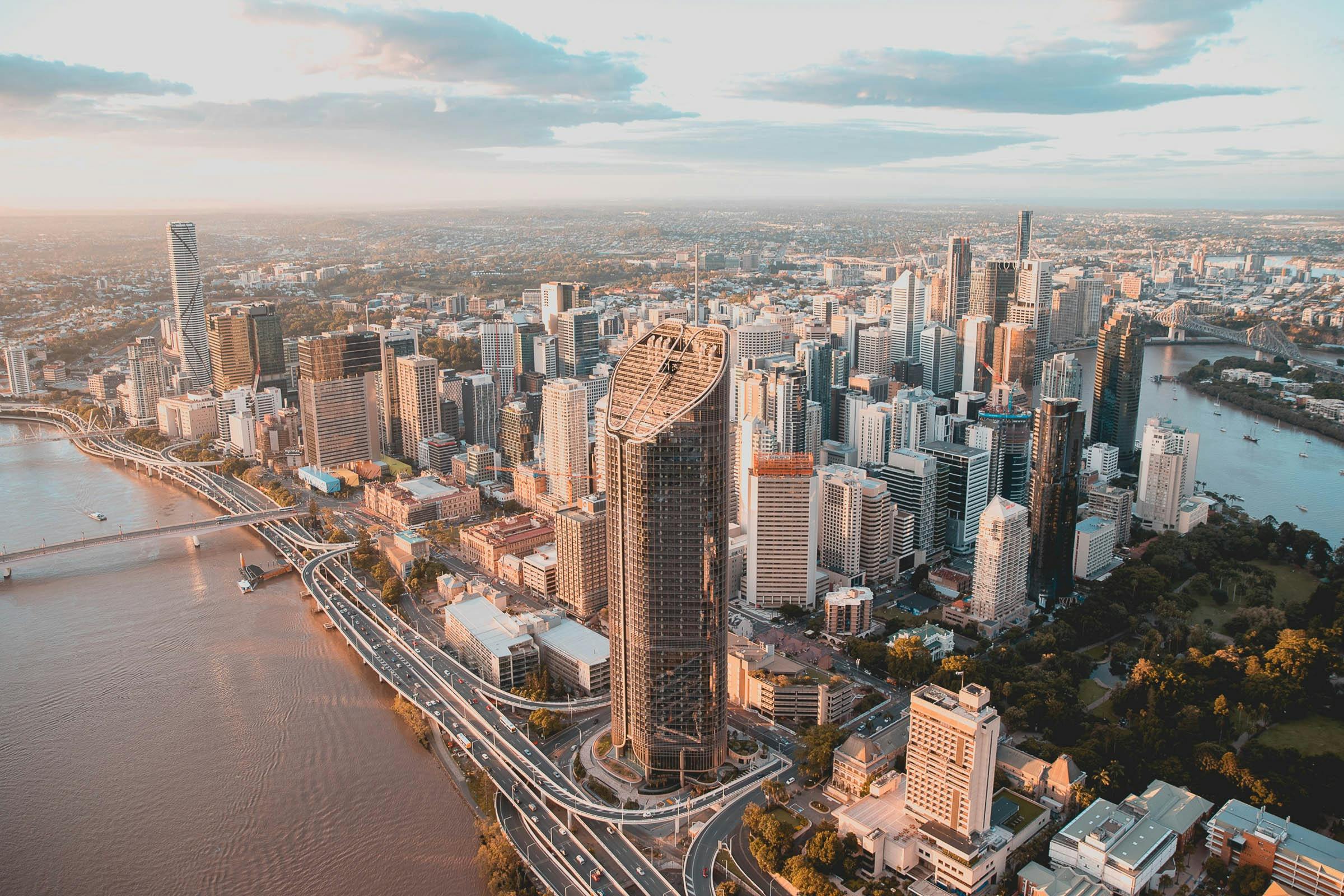 Aerial view of Brisbane CBD skyline at sunset, with the Brisbane River and Story Bridge.
