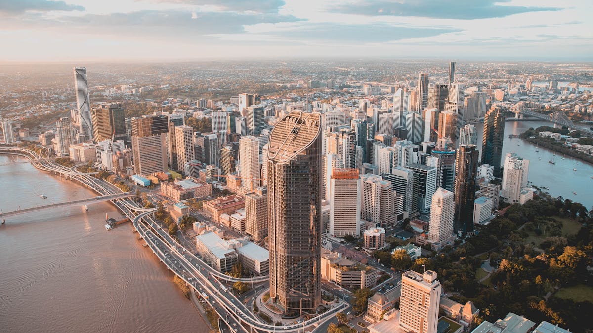 Aerial view of Brisbane CBD skyline at sunset, with the Brisbane River and Story Bridge.