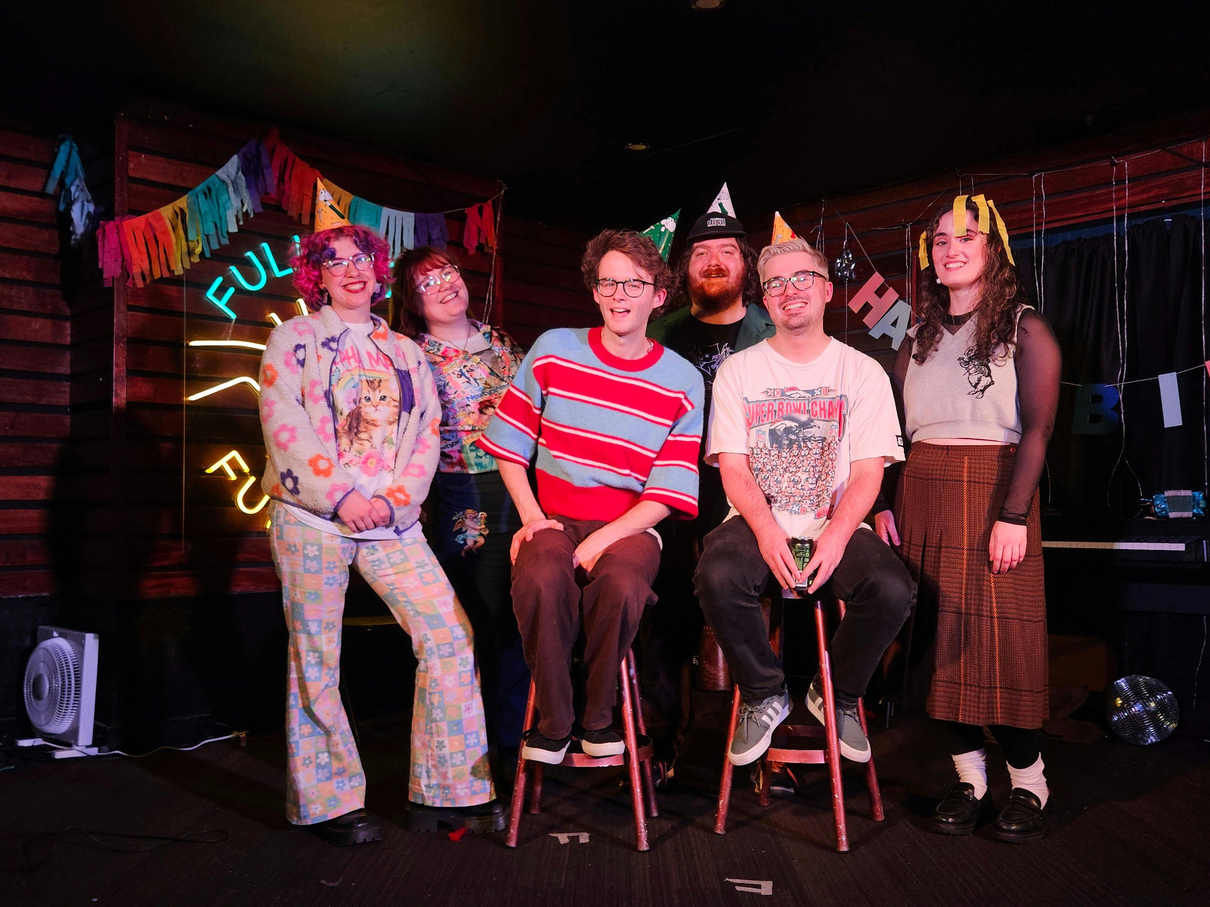 Group of people on stage wearing party hats