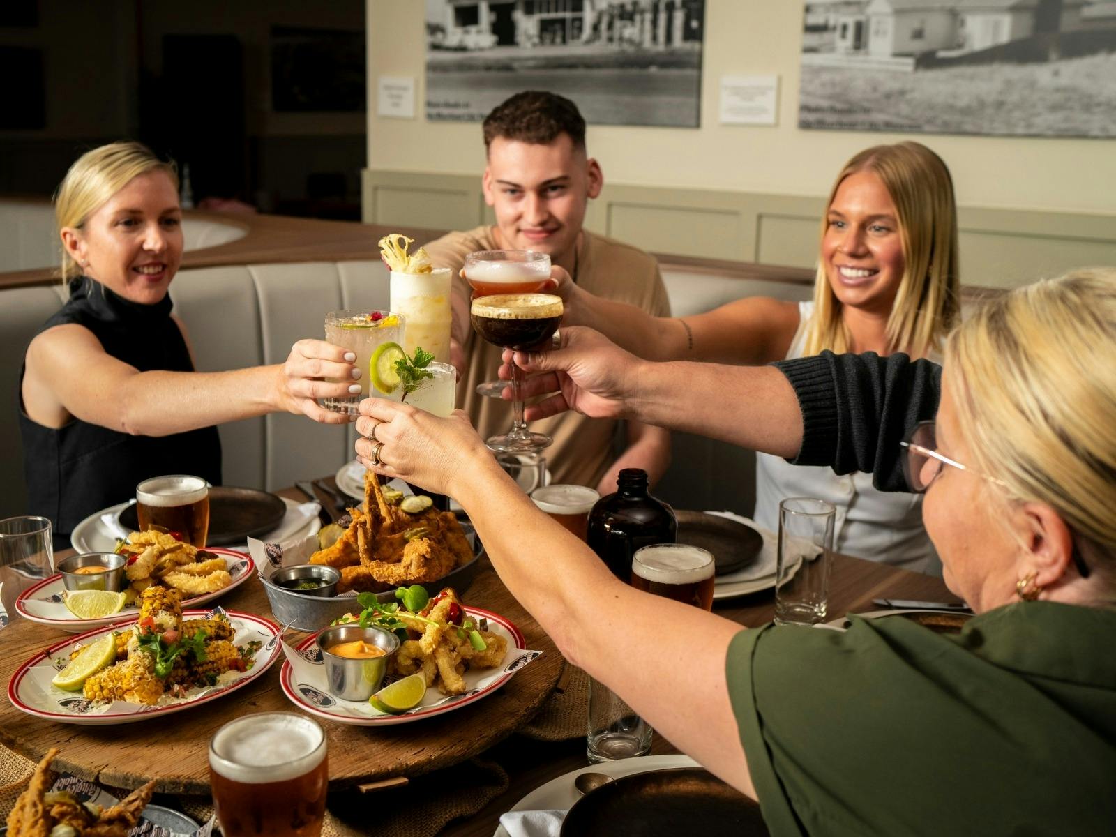 people sitting around a table with food and cheers there drinks together