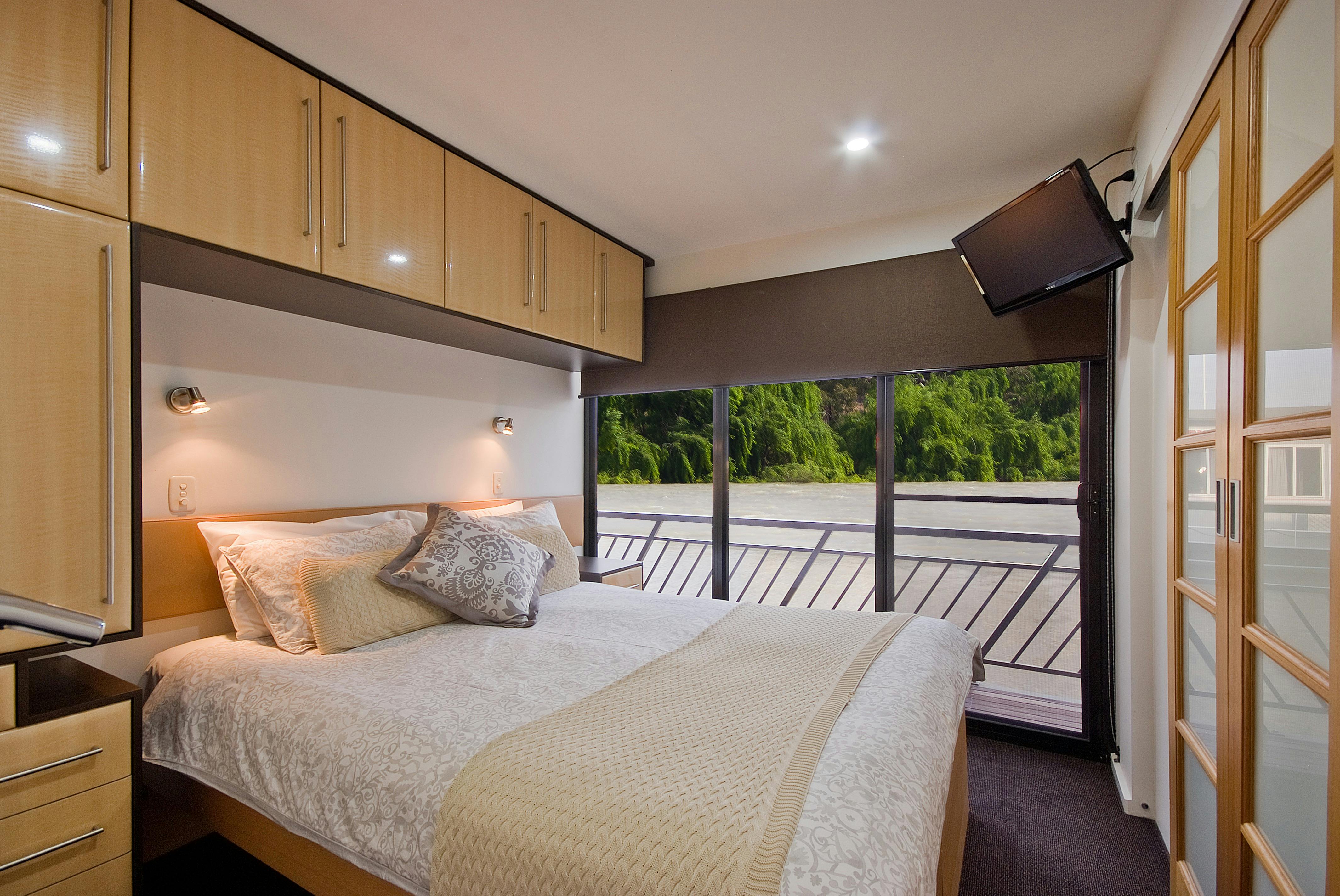 Whitewater bedroom with over head cupboards, large sliding glass doors and ensuite attached.