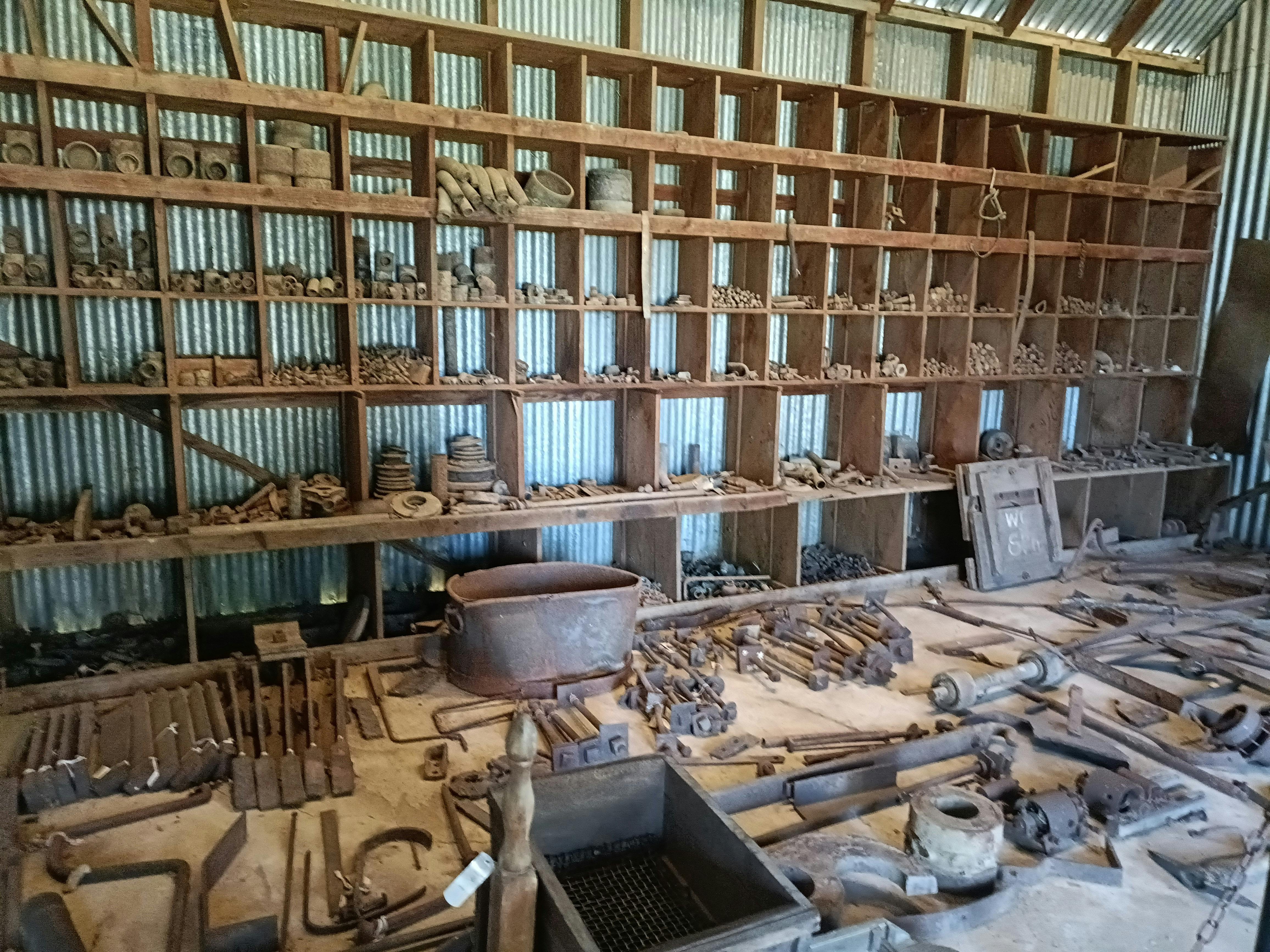Workshop equipment displayed on wall of wooden shelving inside shed