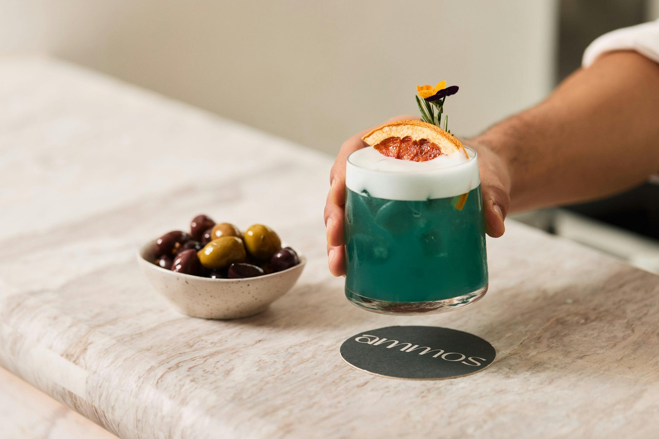 Man putting down cocktail with olives