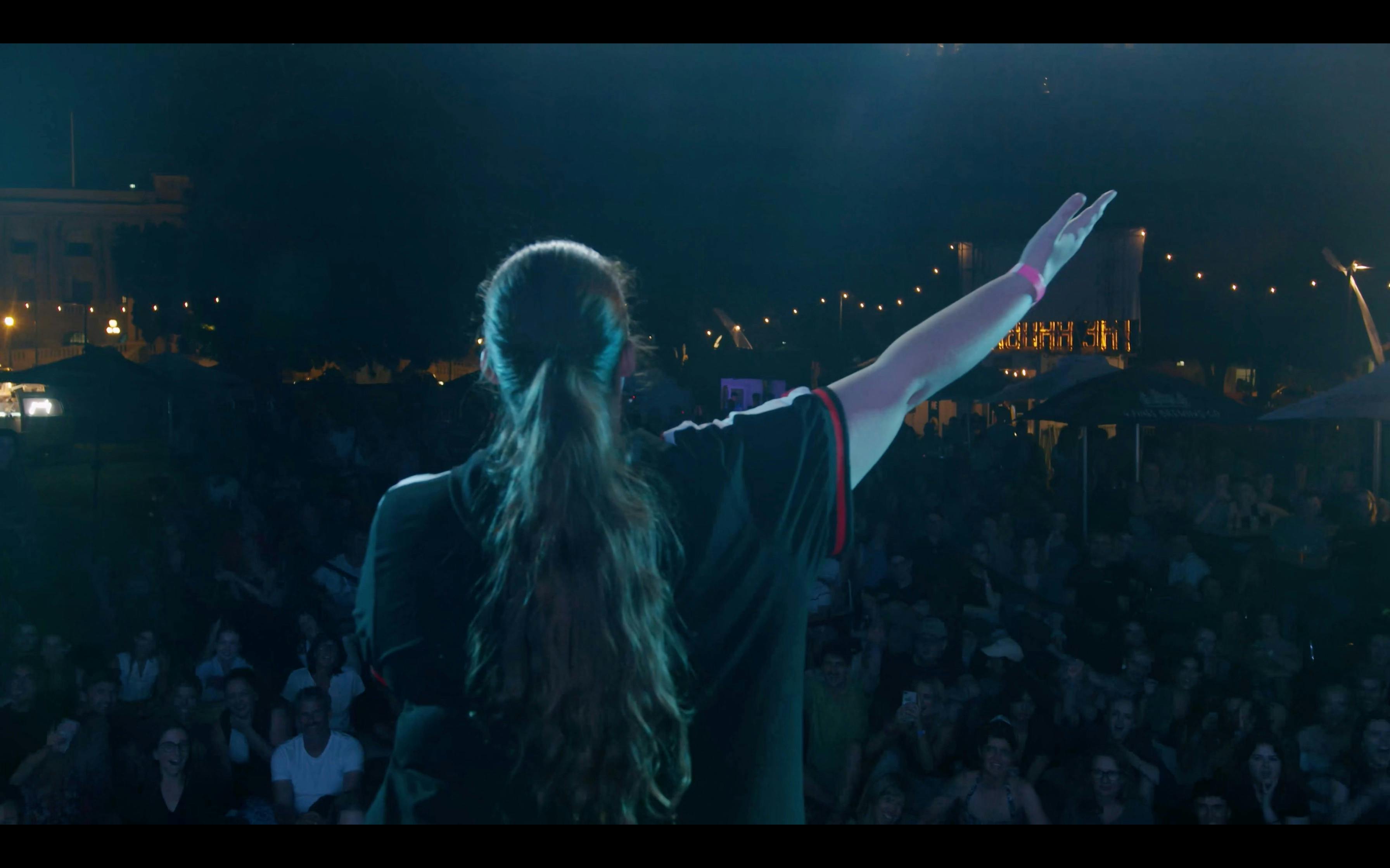 Eddy Rockefeller faces a large crowd with her arm outstretched