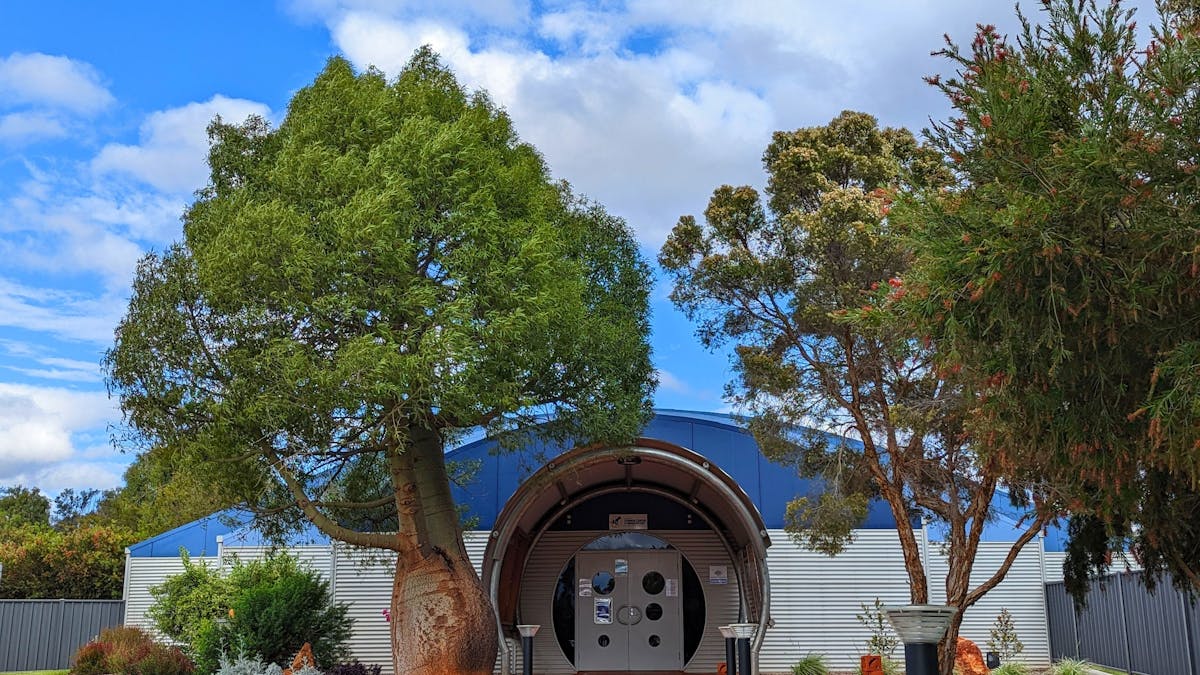 The front entrance of the Cosmos Centre with native Australian flora and green grass along pathway