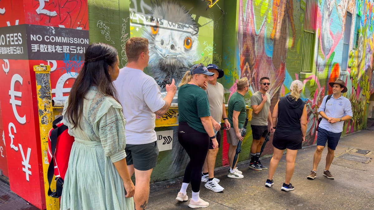 Tour group standing infront of street art with tour guide in a hat