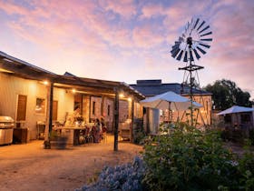 Camp kitchen with fire, small underbench fridge, oven, BBQ, cooking utensils, herb garden, hotplate