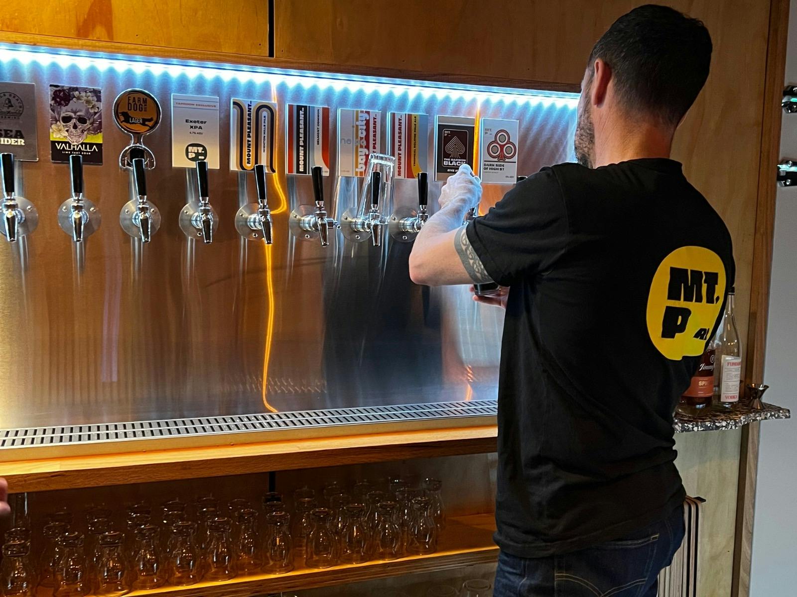Brewers pouring a beer with taps in the background.