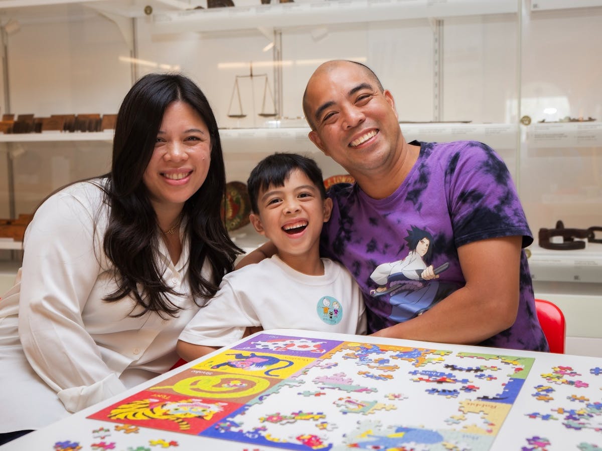 Parents and a young child smiling with a puzzle