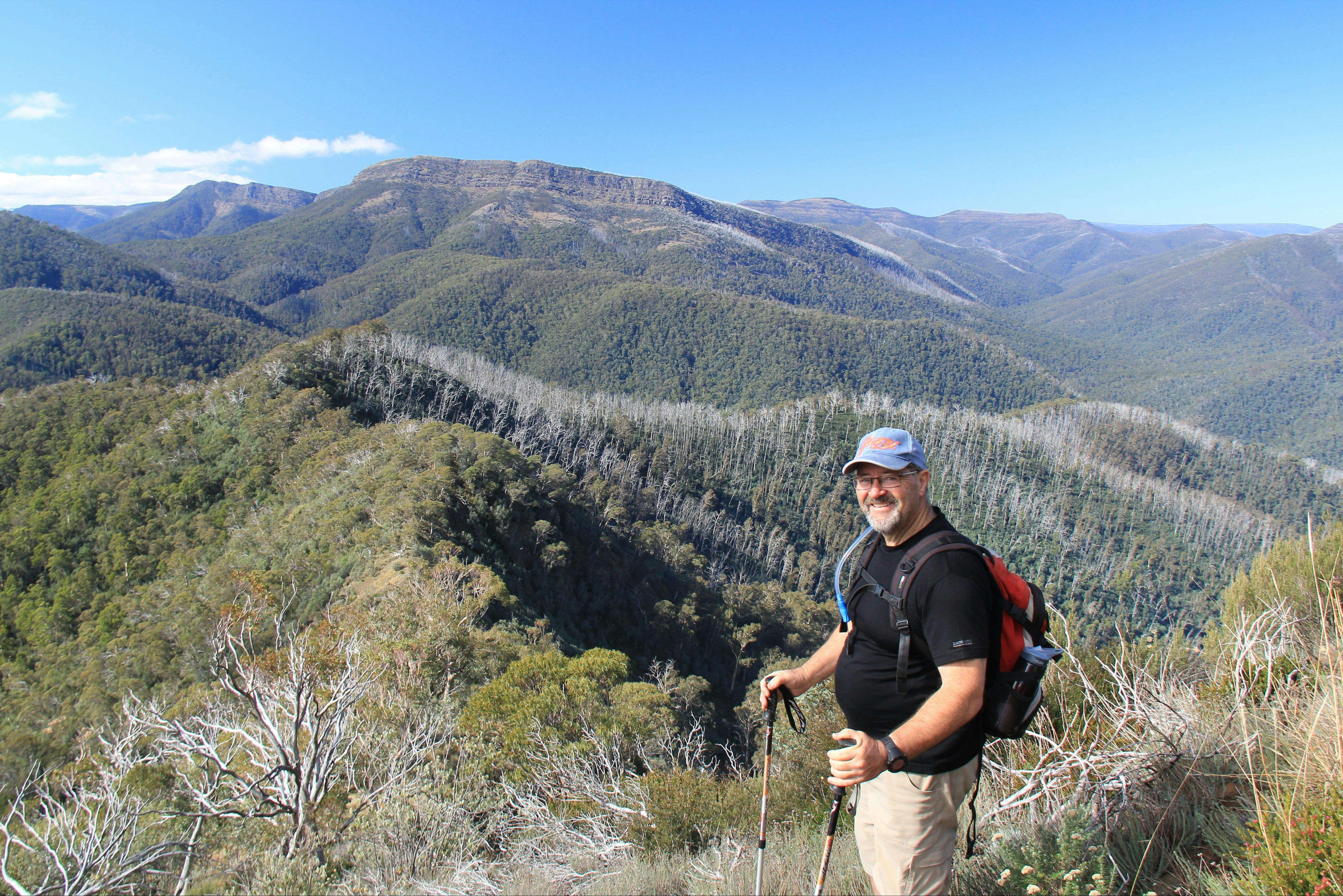 A hiker with a brilliant view of The Bluff and Mt Eadley Stoney, and The Crosscut Saw on the horizon